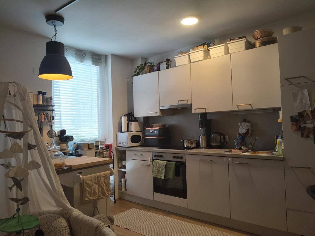 Helle Küche mit modernen Schränken, Kochbereich und einem Fenster mit Jalousien.