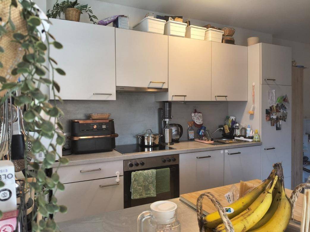 Moderne Küche mit hellgrauen Schränken, integriertem Kochfeld und Backofen, sowie einer Arbeitsplatte.