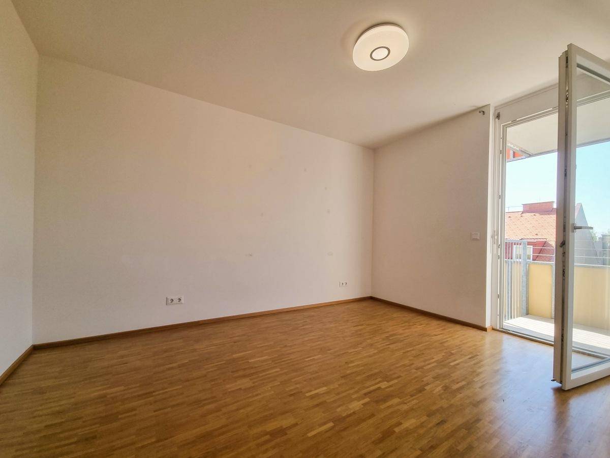 Helles Schlafzimmer mit Parkettboden und direktem Zugang zum Balkon.