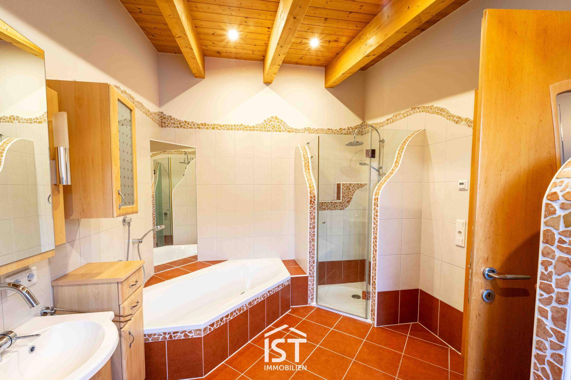 Badezimmer mit Eckbadewanne, Duschkabine und rustikalen Fliesen in Erdtönen.
