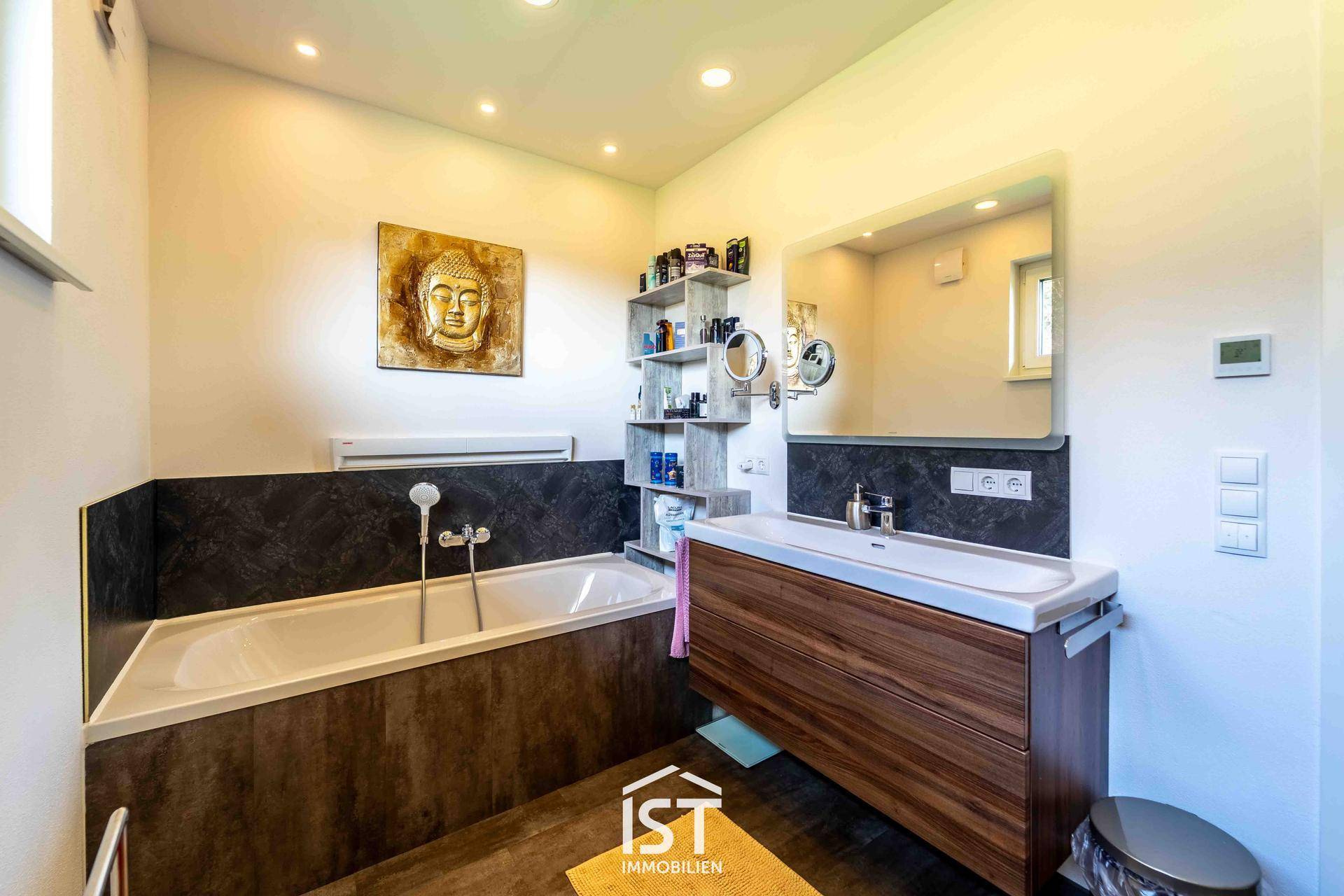 Modernes Badezimmer mit Badewanne, Einzelwaschbecken und dunklen Wandfliesen.