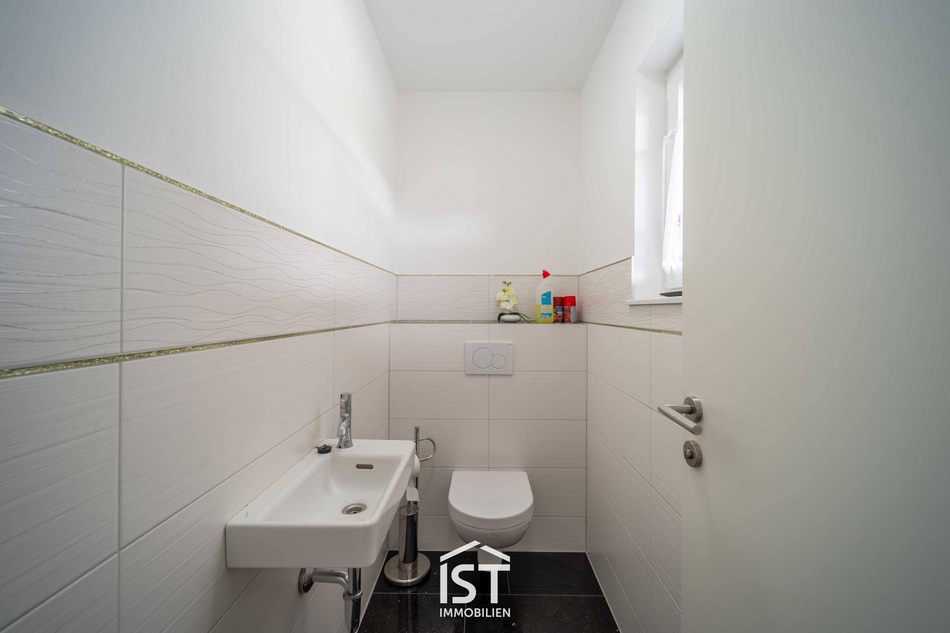 Kleines Gäste-WC mit weißen Fliesen, wandhängendem WC und Fenster.