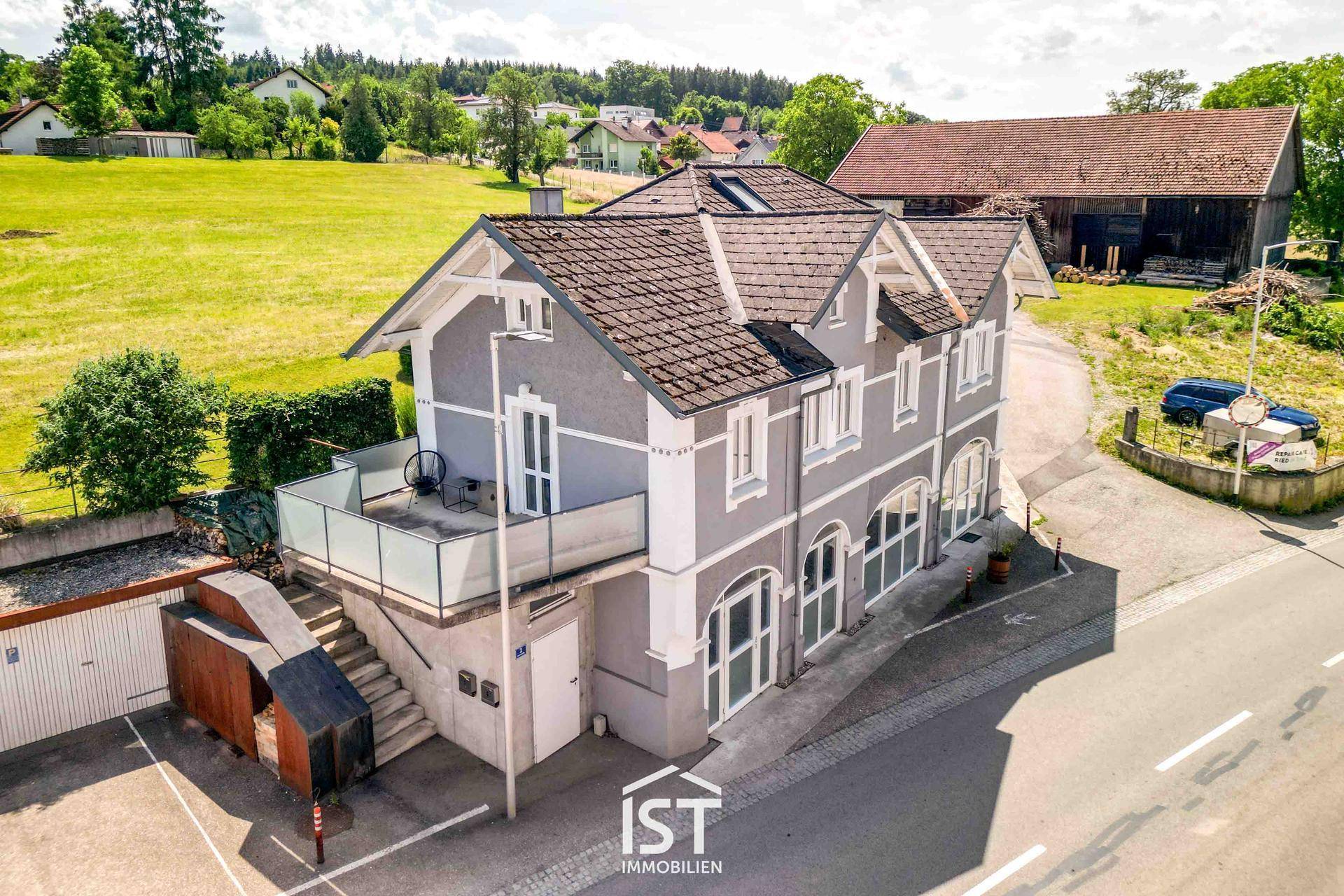 Rückansicht des Gebäudes mit Balkon und Blick auf grüne Felder und ländliche Umgebung.