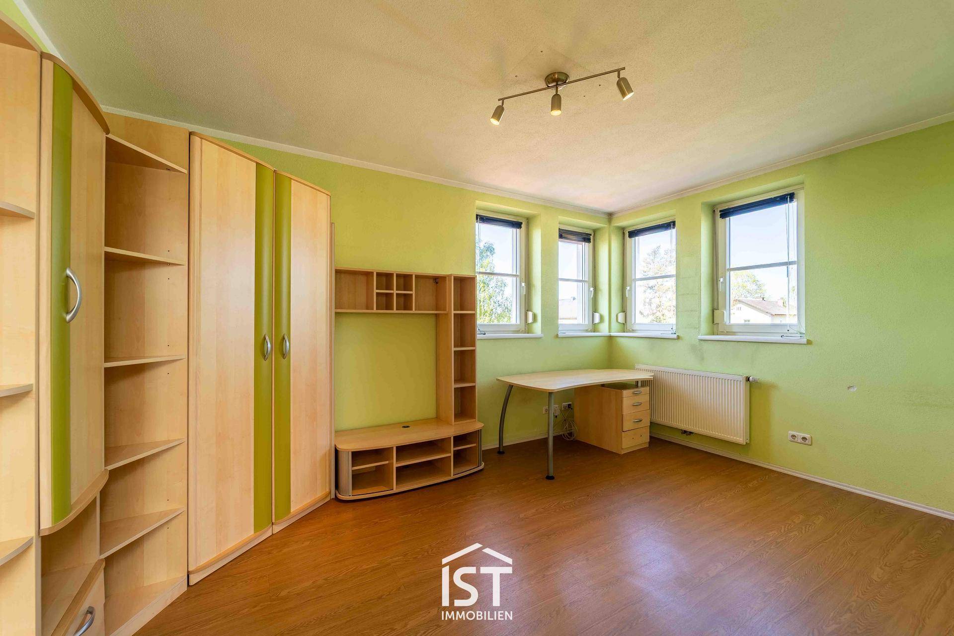 Kinderzimmer mit grün gestrichenen Wänden, Schrank und Schreibtisch.