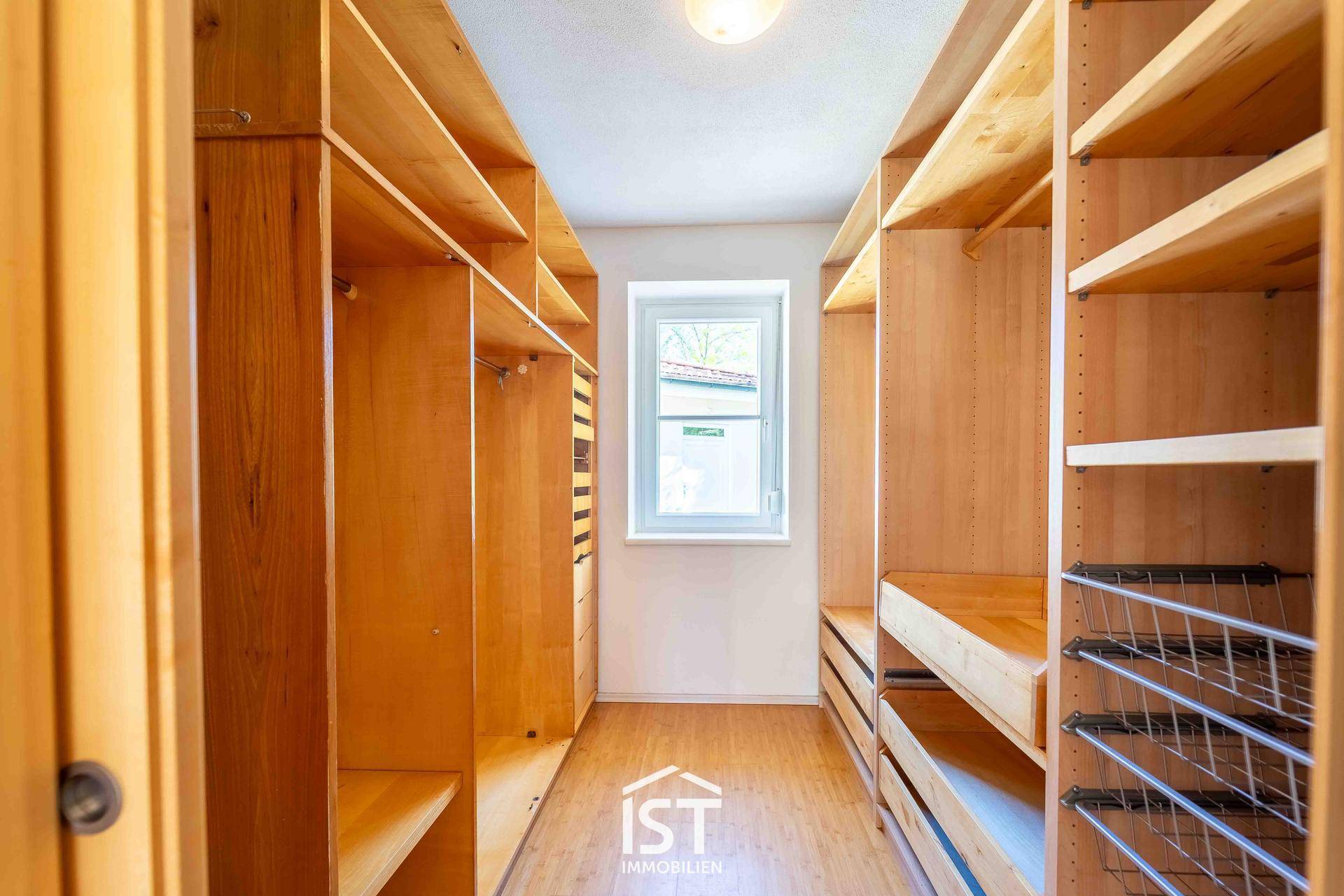 Geräumiges Ankleidezimmer mit maßgefertigten Holzregalen und Fenster für Tageslicht.
