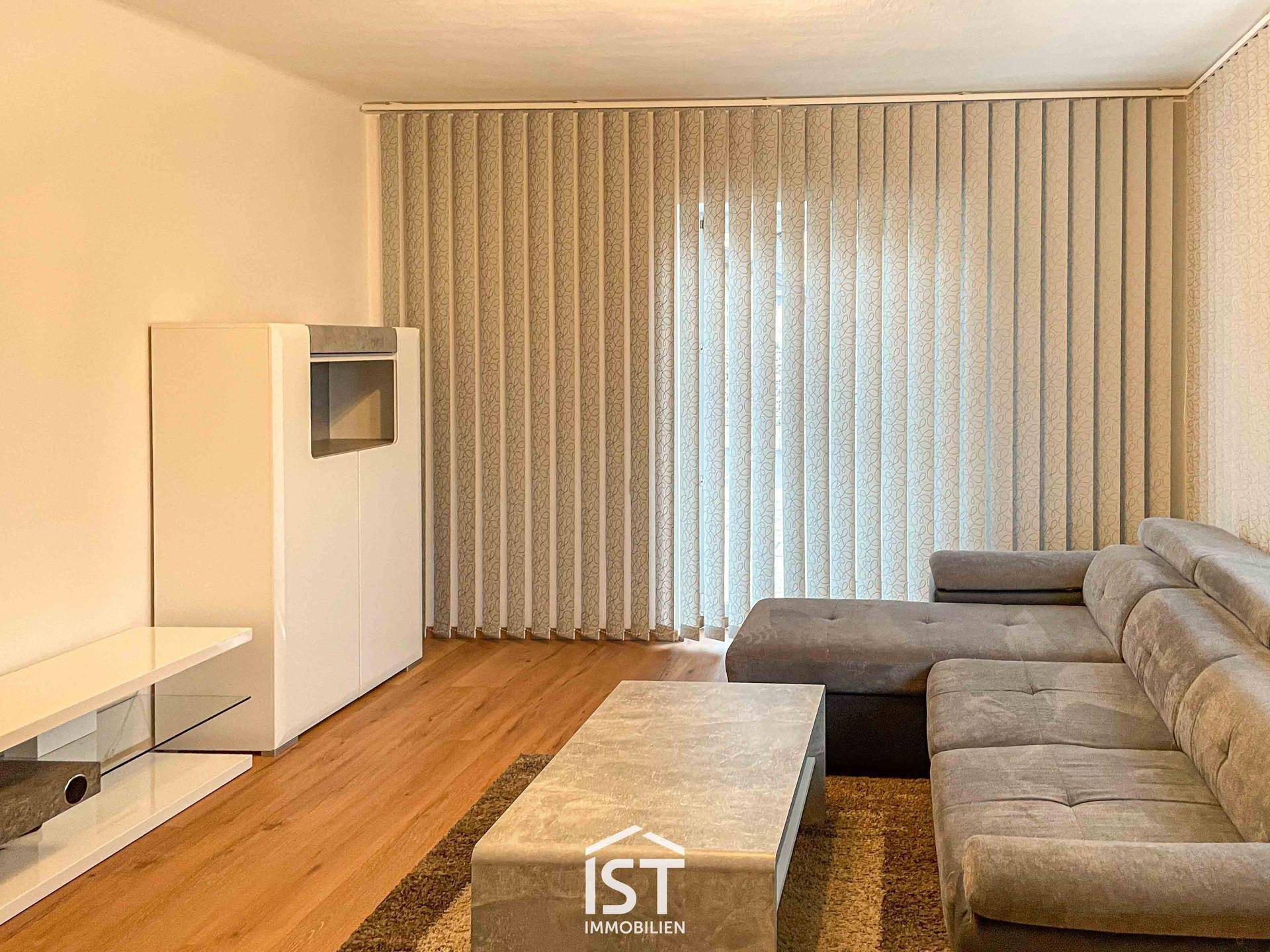 Gemütliches Wohnzimmer mit großem Ecksofa, Holzboden und einem modernen Kaminofen.