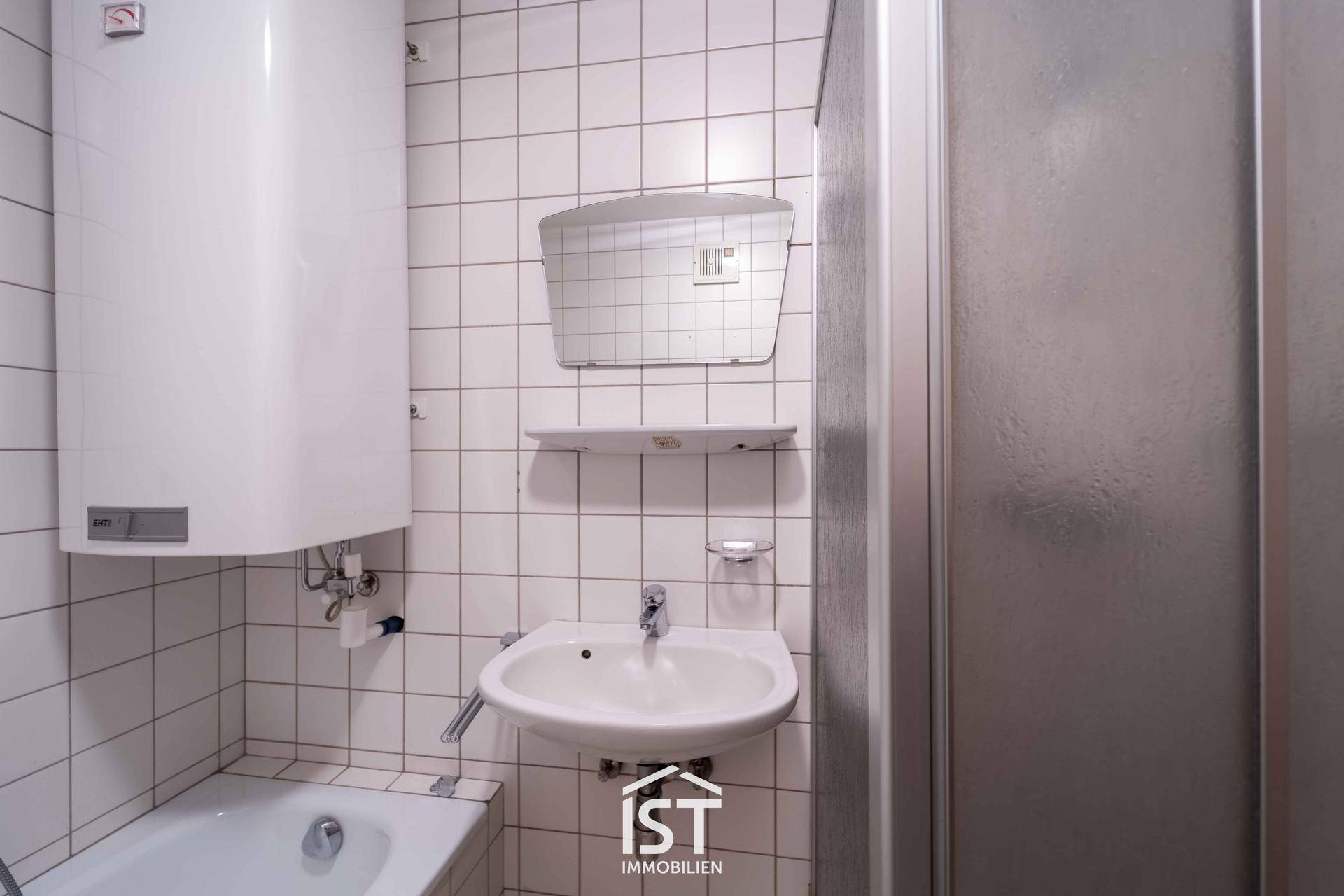 Gefliestes Badezimmer mit Badewanne, Waschbecken, Spiegel und Duschkabine.