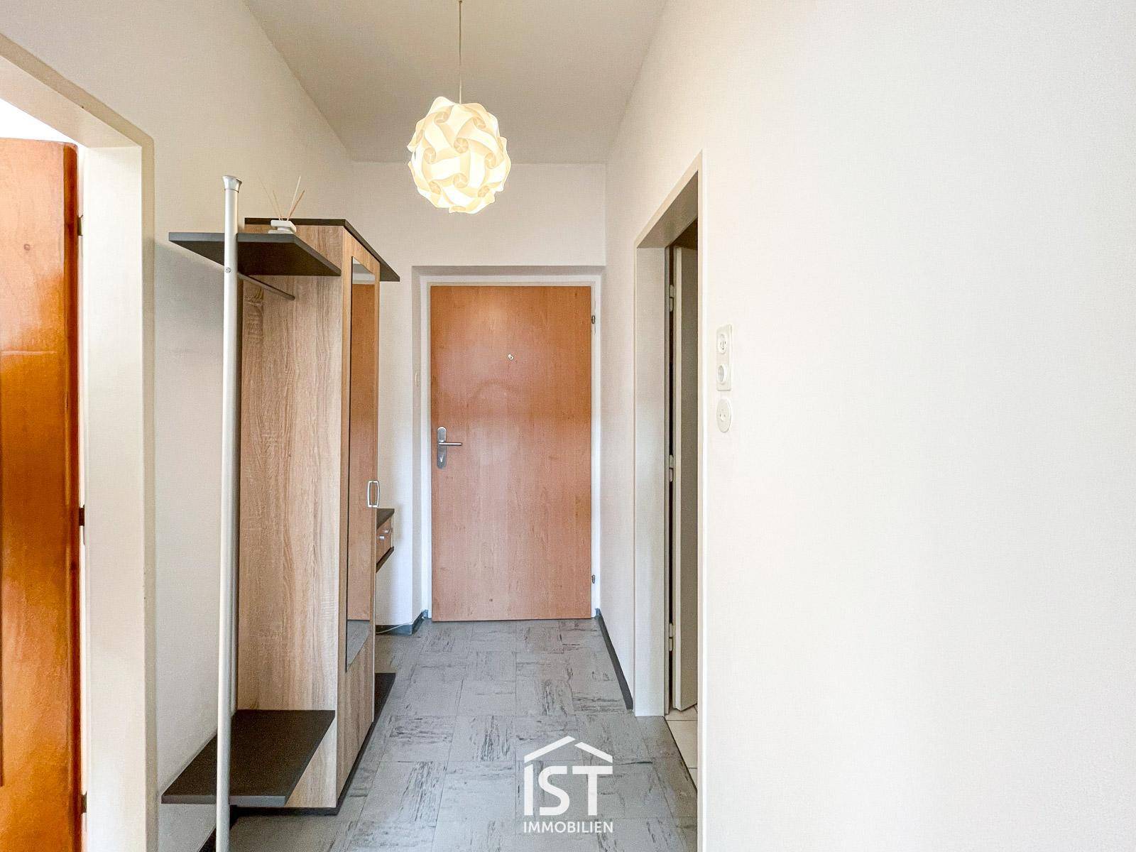 Heller Flur mit Garderobe und Zugang zu weiteren Räumen, ausgestattet mit praktischem Bodenbelag.