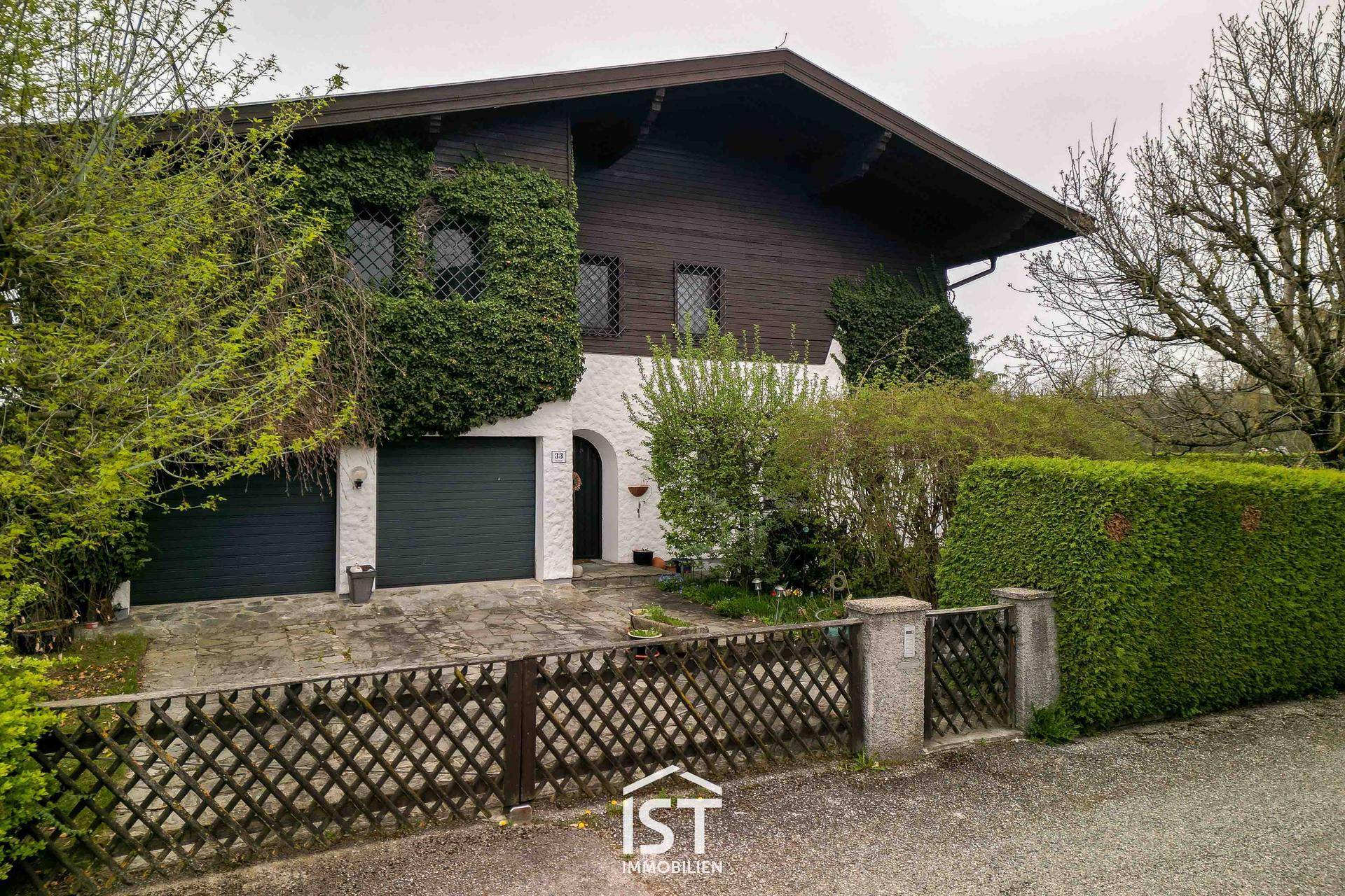 Vorderansicht des Hauses mit begrüntem Eingangsbereich, Doppelgarage und gepflegter Hecke.