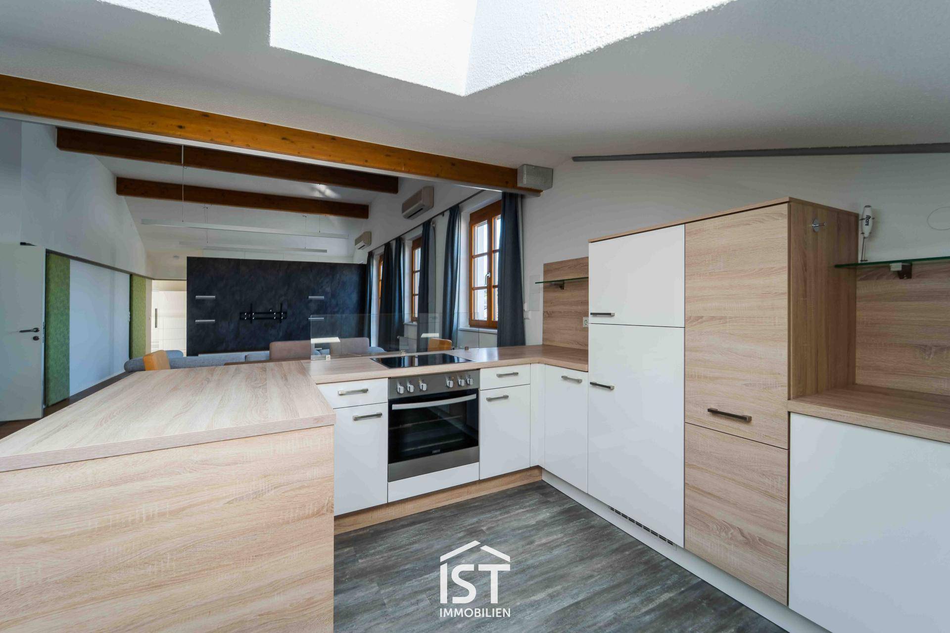 Moderne Einbauküche mit Holz- und weißen Fronten, integrierten Geräten und Dachfenstern.