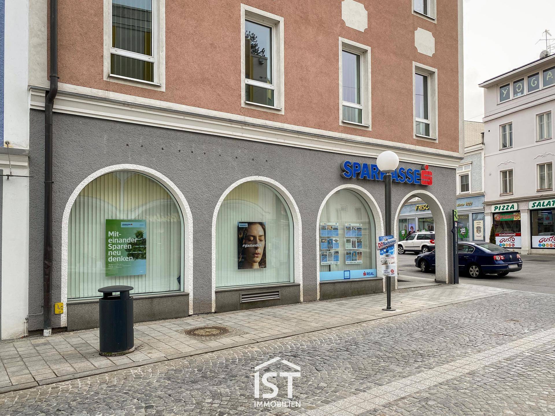 Nahaufnahme der Geschäftsfassade mit großen Schaufenstern und einem Eingangsbereich der Sparkasse im Erdgeschoss.