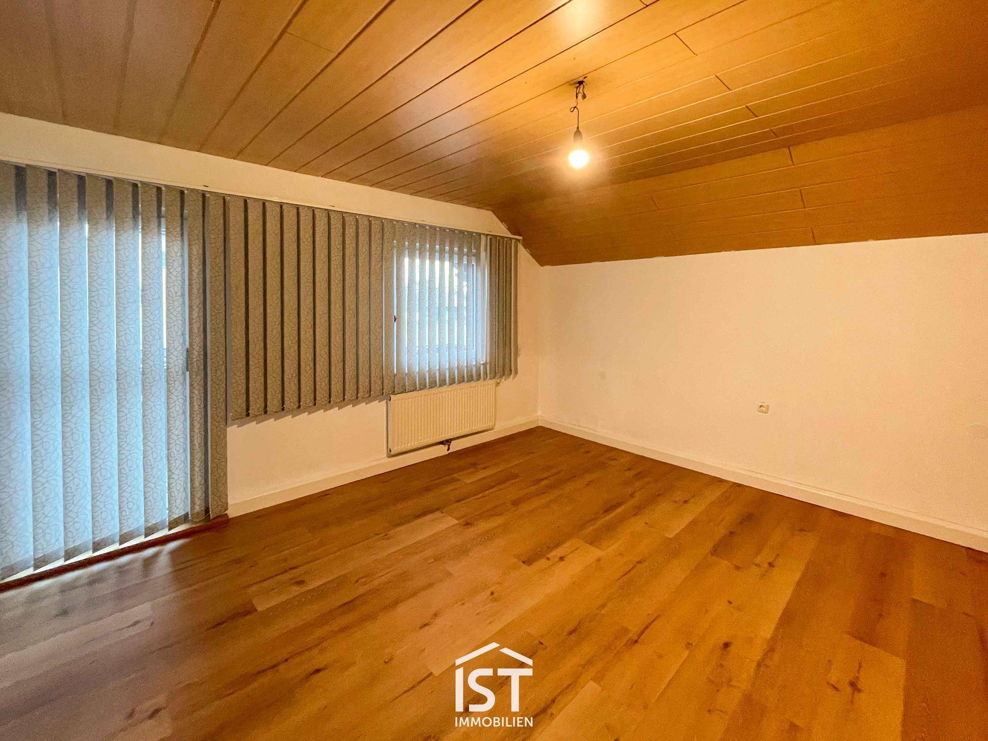 Geräumiges Schlafzimmer mit Holzboden, Holzdecke und großen Fenstern für viel Tageslicht.
