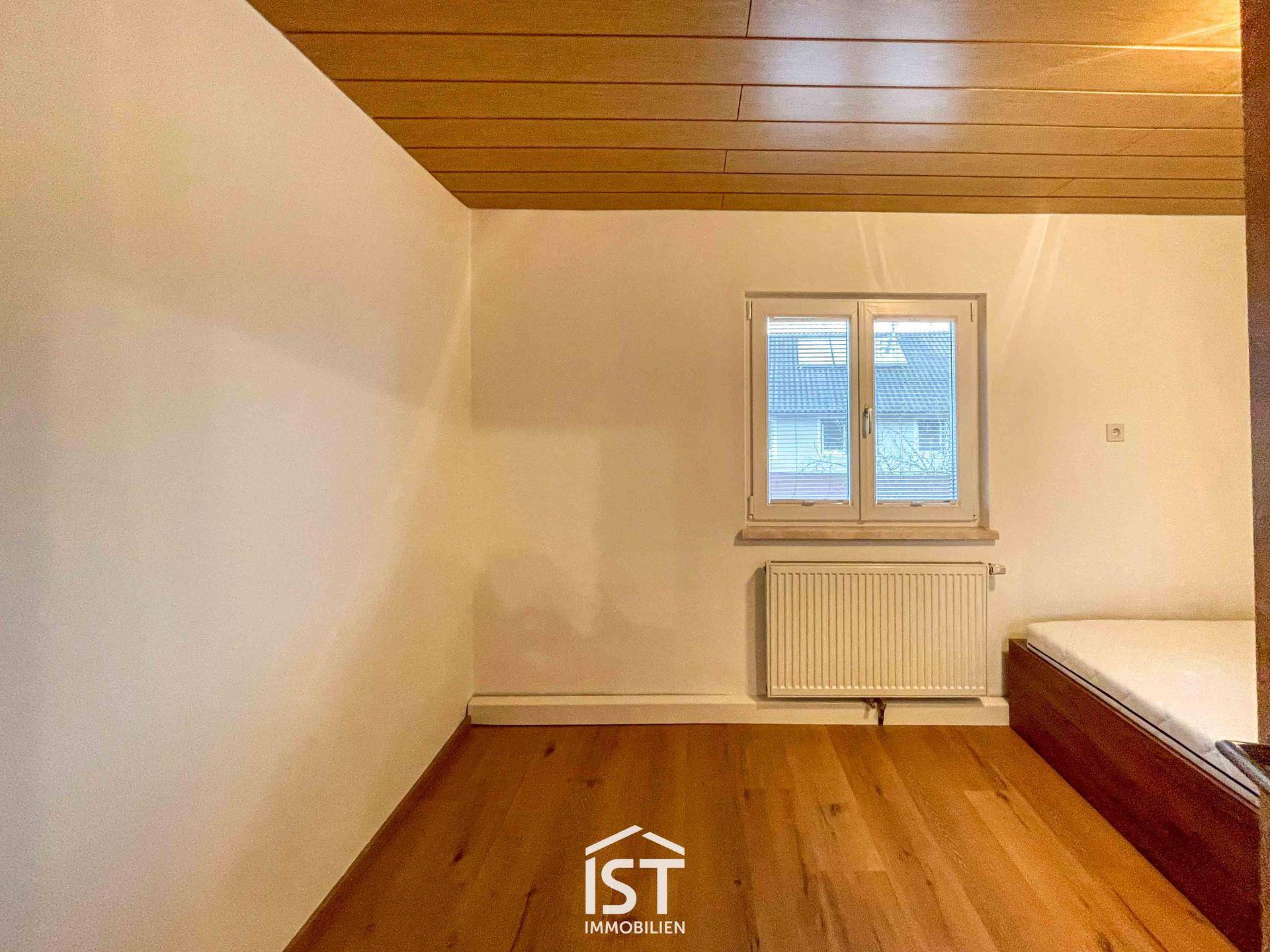 Gemütliches Schlafzimmer mit Holzboden, Holzdecke und einem Fenster mit Blick auf die Nachbarschaft.