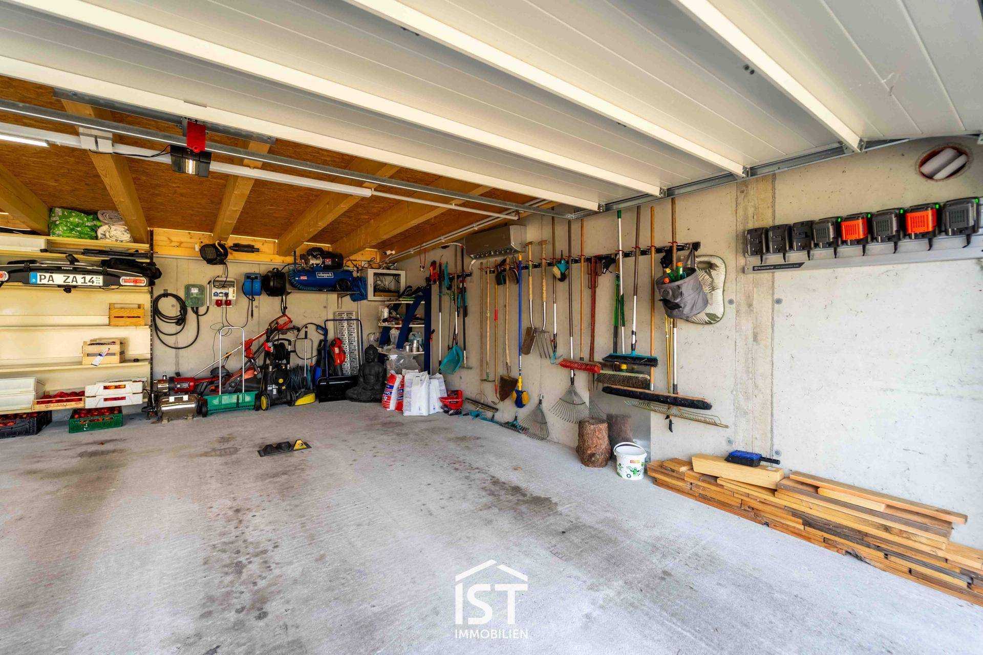 Geräumige Garage mit viel Stauraum, Werkzeugen und Betonboden.