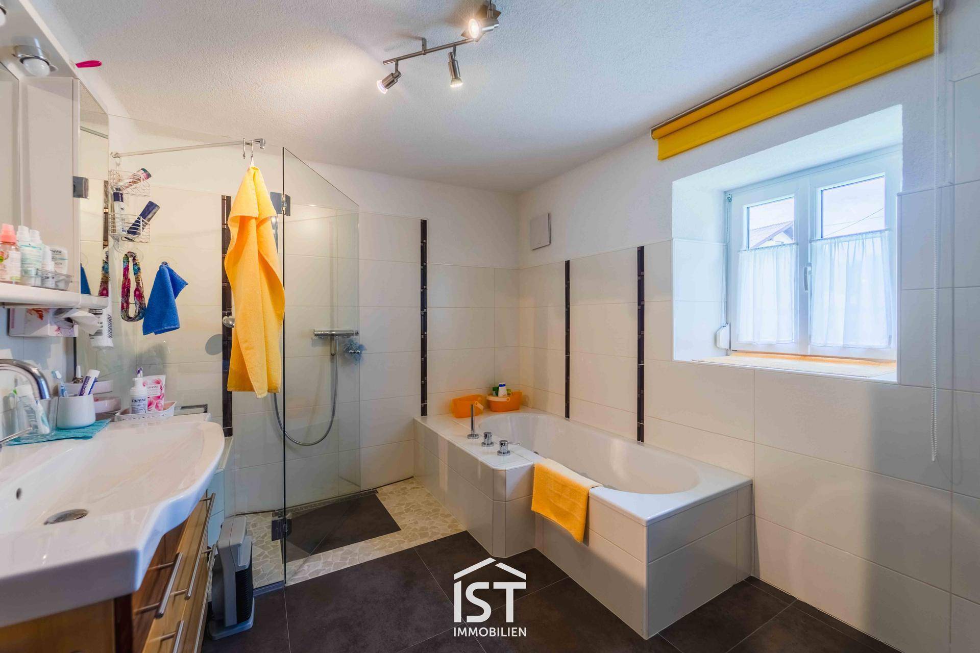 Helles Badezimmer mit Badewanne, separater Dusche und Fenster für natürliche Belüftung.