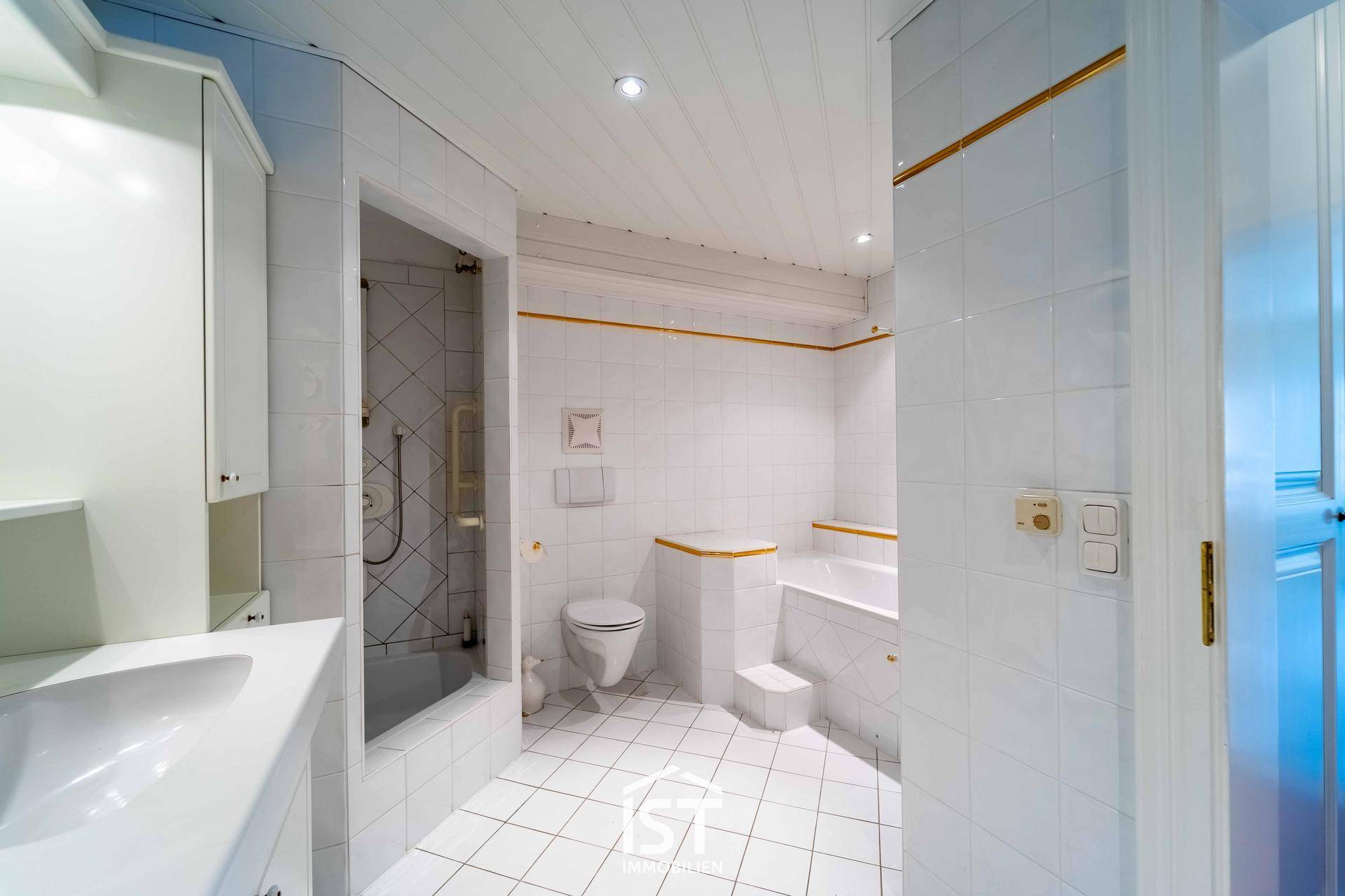 Helles Badezimmer mit weißen Fliesen, Badewanne und separater Dusche.