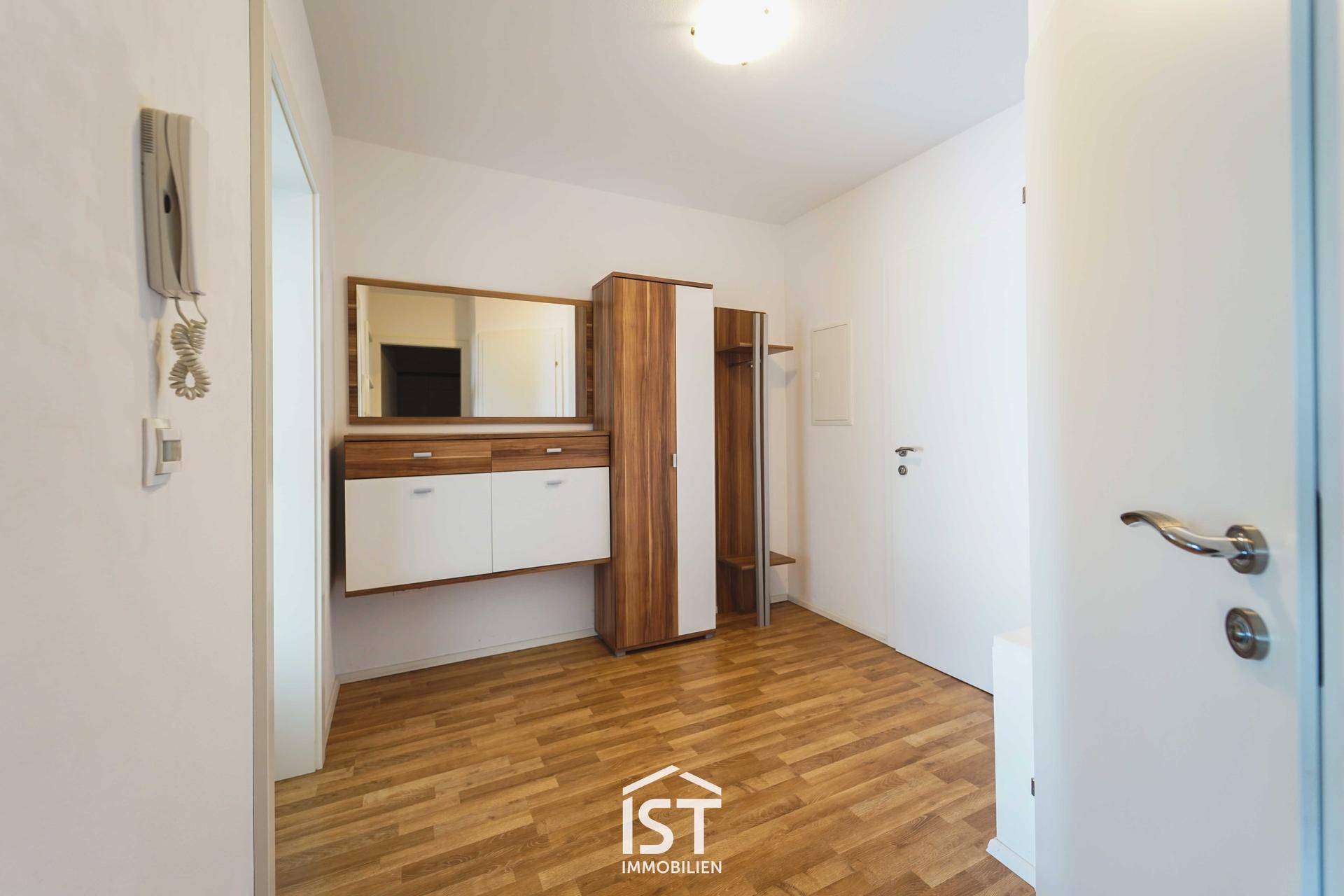 Eingangsbereich mit Holzboden, Garderobe, Spiegel und Gegensprechanlage.