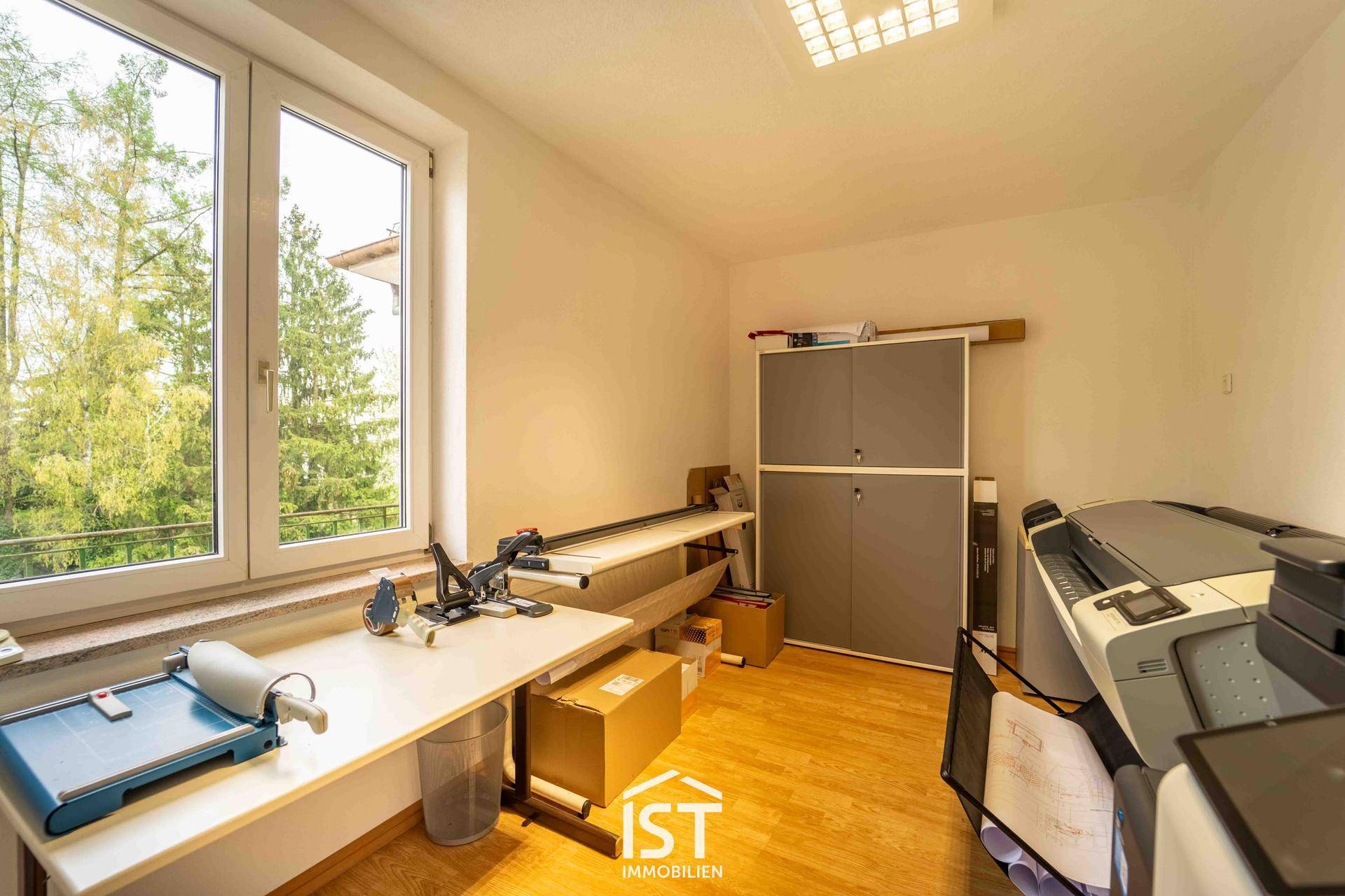 Funktionaler Arbeitsraum mit großen Fenstern, Blick ins Grüne und Stauraum, ideal für Druck- und Bastelarbeiten.
