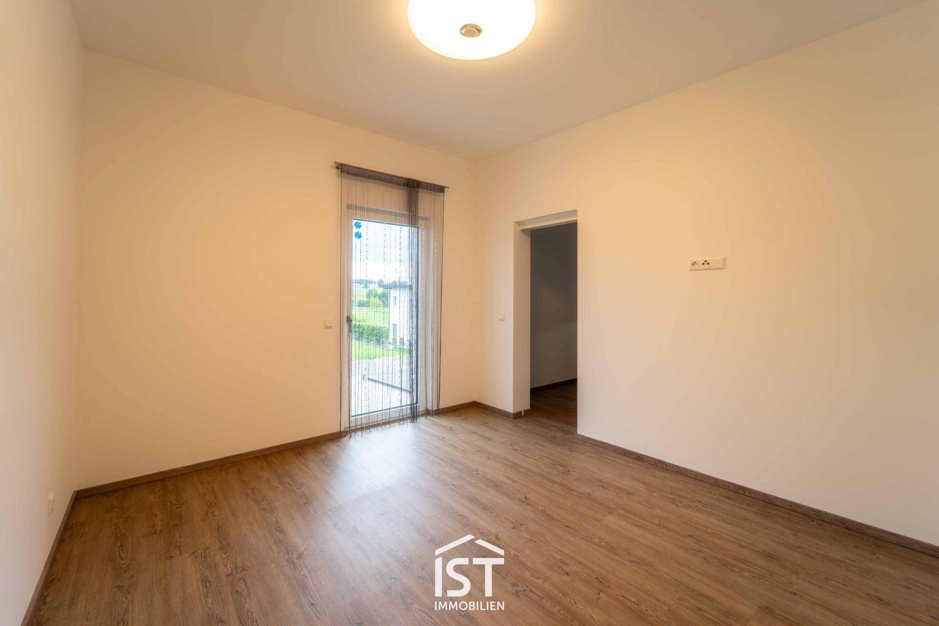 Geräumiges Zimmer mit Laminatboden und Zugang zu einem Außenbereich.