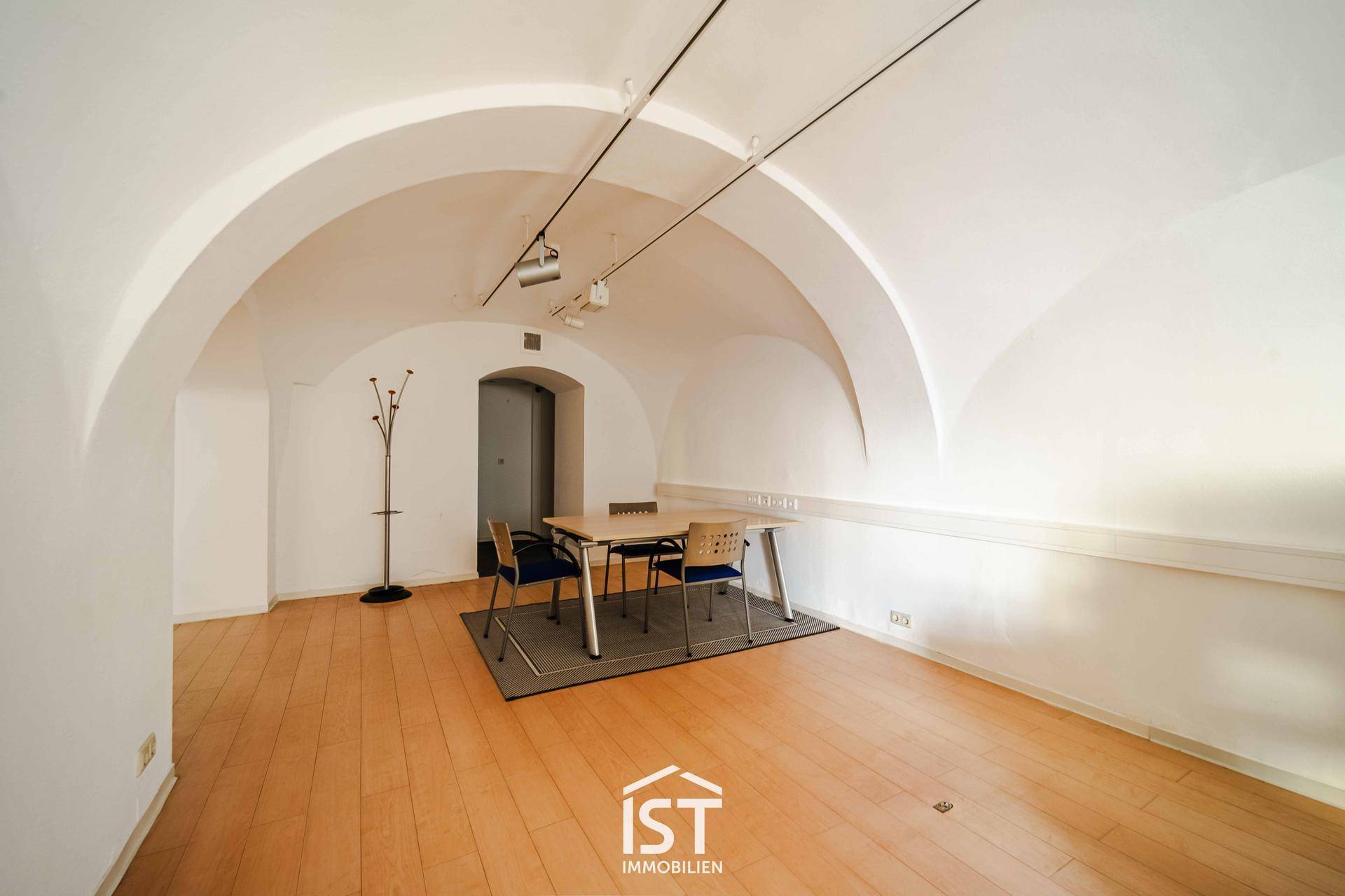 Großer, heller Büroraum mit beeindruckenden Gewölbedecken, Holzboden und einem Besprechungstisch im hinteren Bereich.