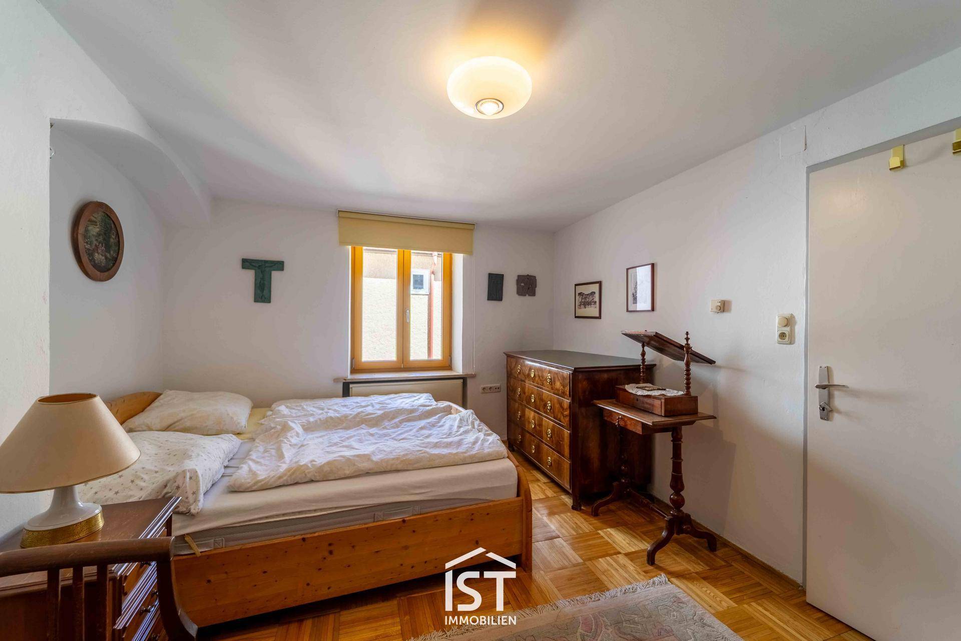 Schlafzimmer mit Holzbett, Kommode und Parkettboden, traditionell eingerichtet.