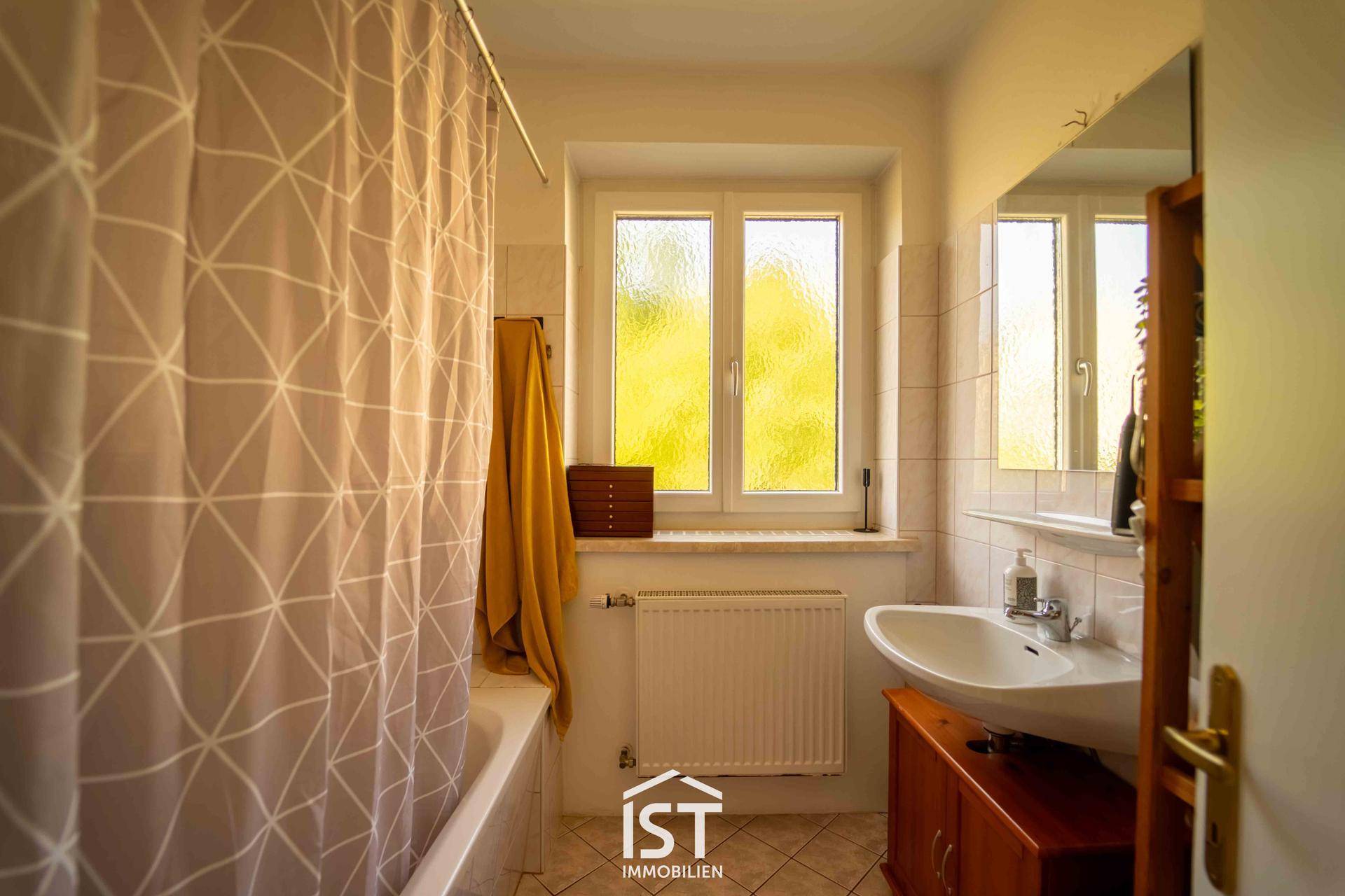 Badezimmer mit Badewanne, Einzelwaschbecken und einem Fenster für natürliche Belüftung.