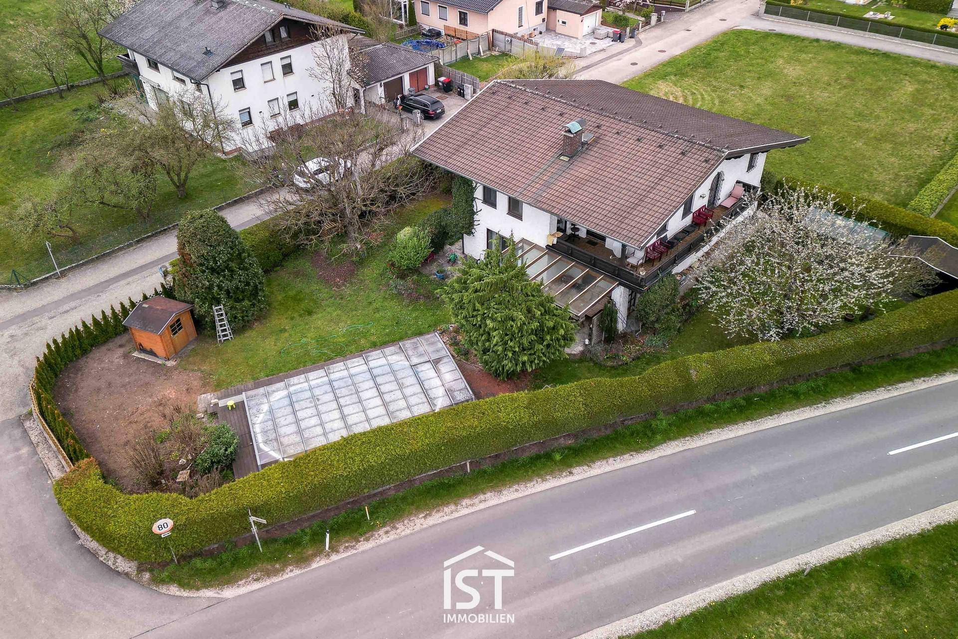 Luftaufnahme des Anwesens mit großem Garten, Pool und umgebender Hecke.