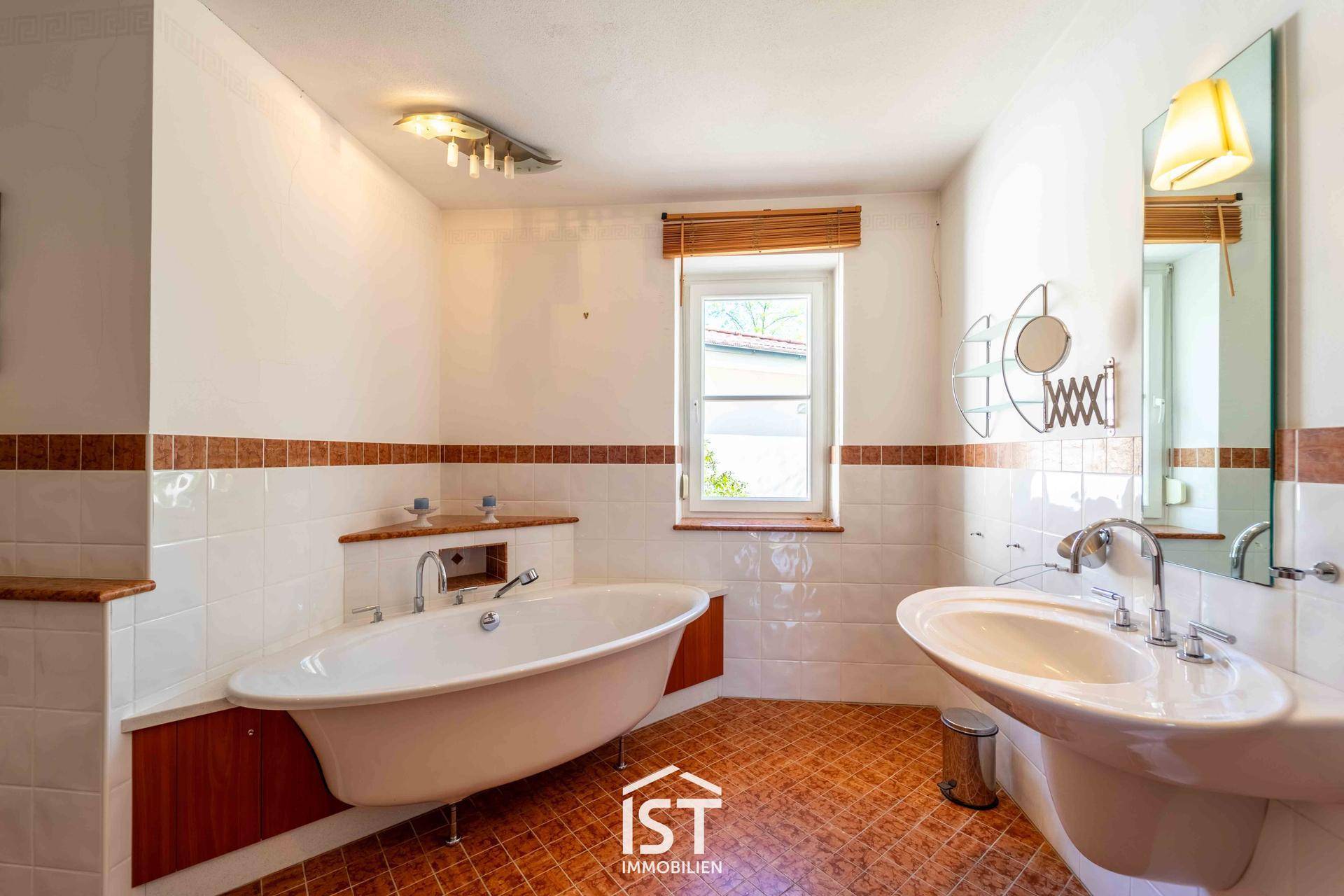 Badezimmer mit Badewanne, Einzelwaschbecken und traditionellen Fliesen in warmen Farbtönen.
