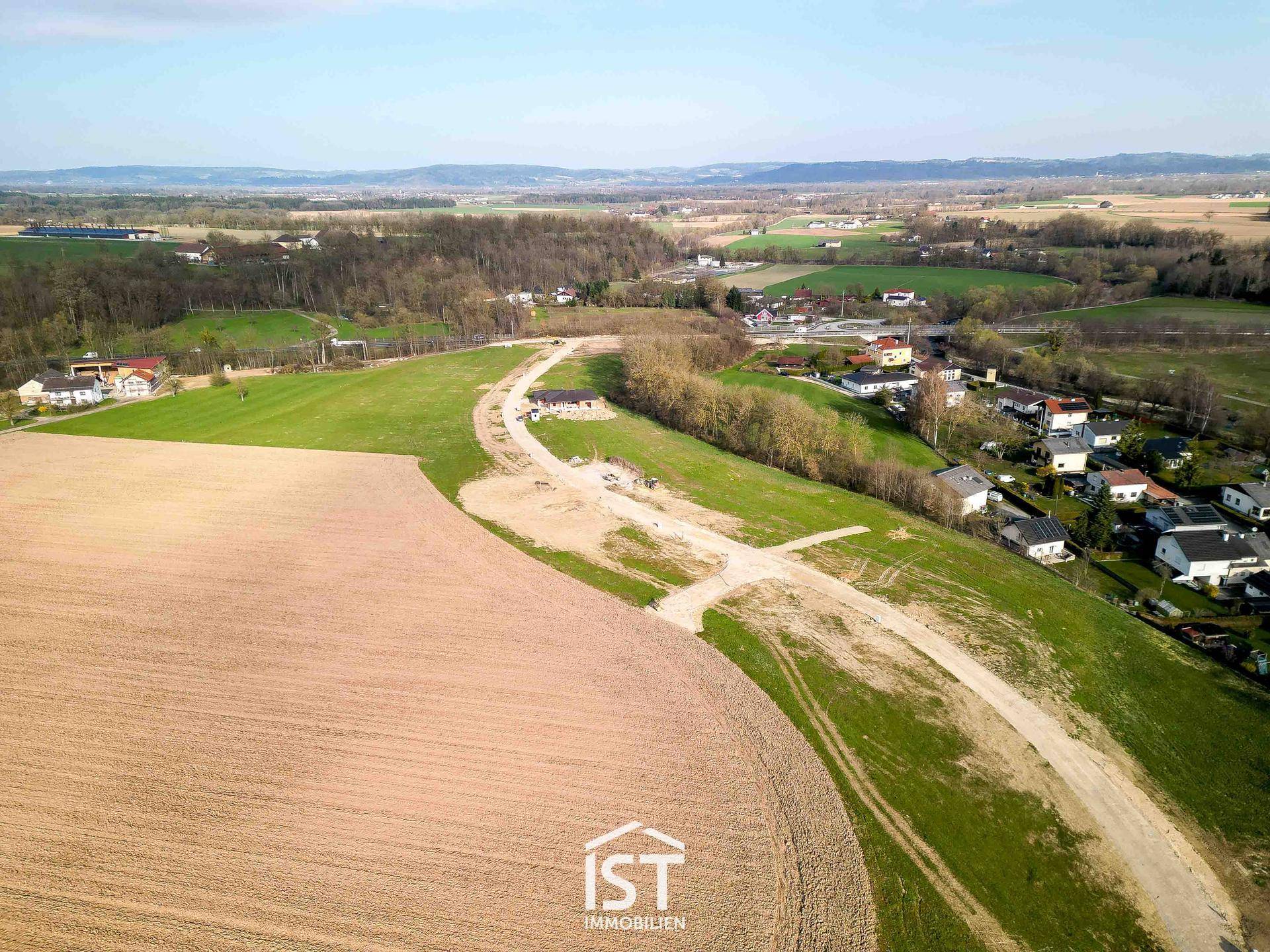 Panoramablick aus der Luft auf eine ländliche Siedlung mit Feldern und neu angelegten Wegen.