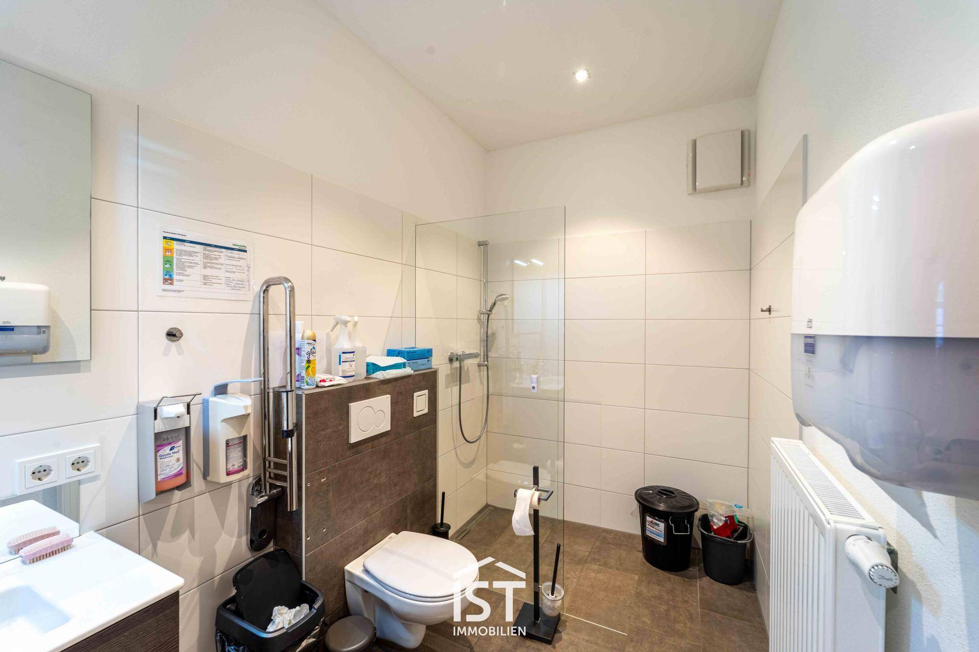 Modernes Badezimmer mit barrierefreier Dusche, Toilette und Haltegriffen für Komfort.