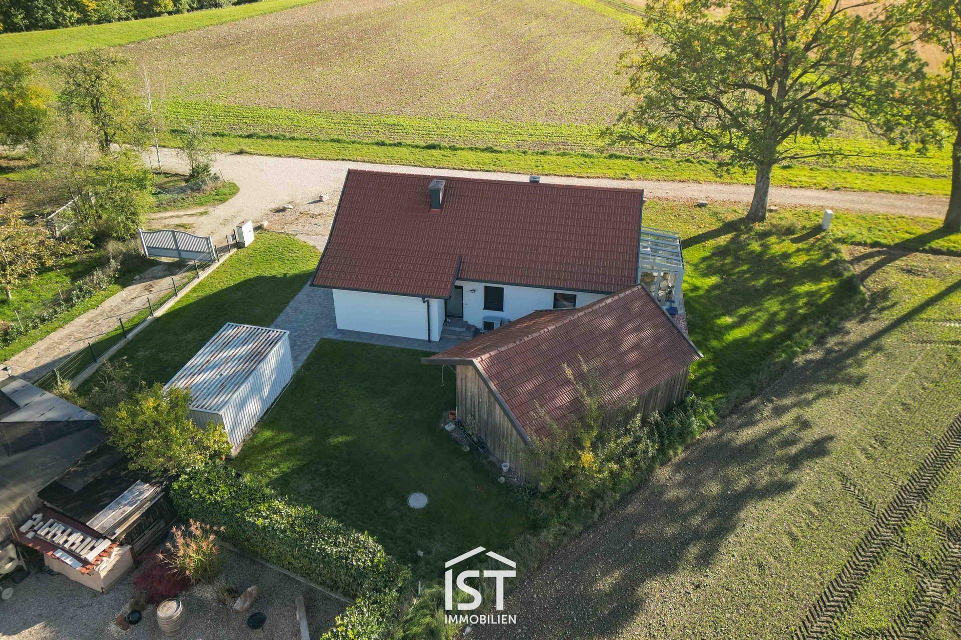 Luftaufnahme des Hauses von hinten, zeigt einen Geräteschuppen und weite Felder.