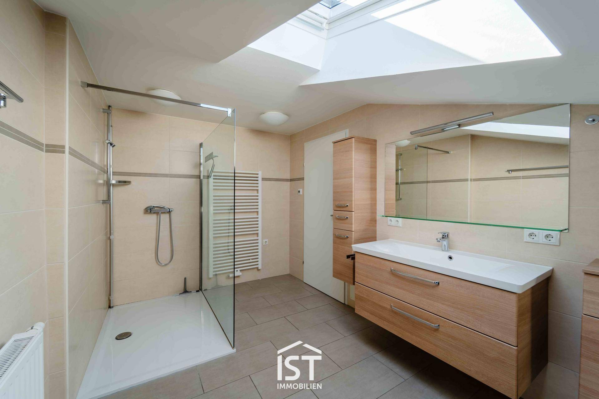 Modernes Badezimmer mit begehbarer Dusche, Holzwaschtisch und Dachfenster für natürliches Licht.