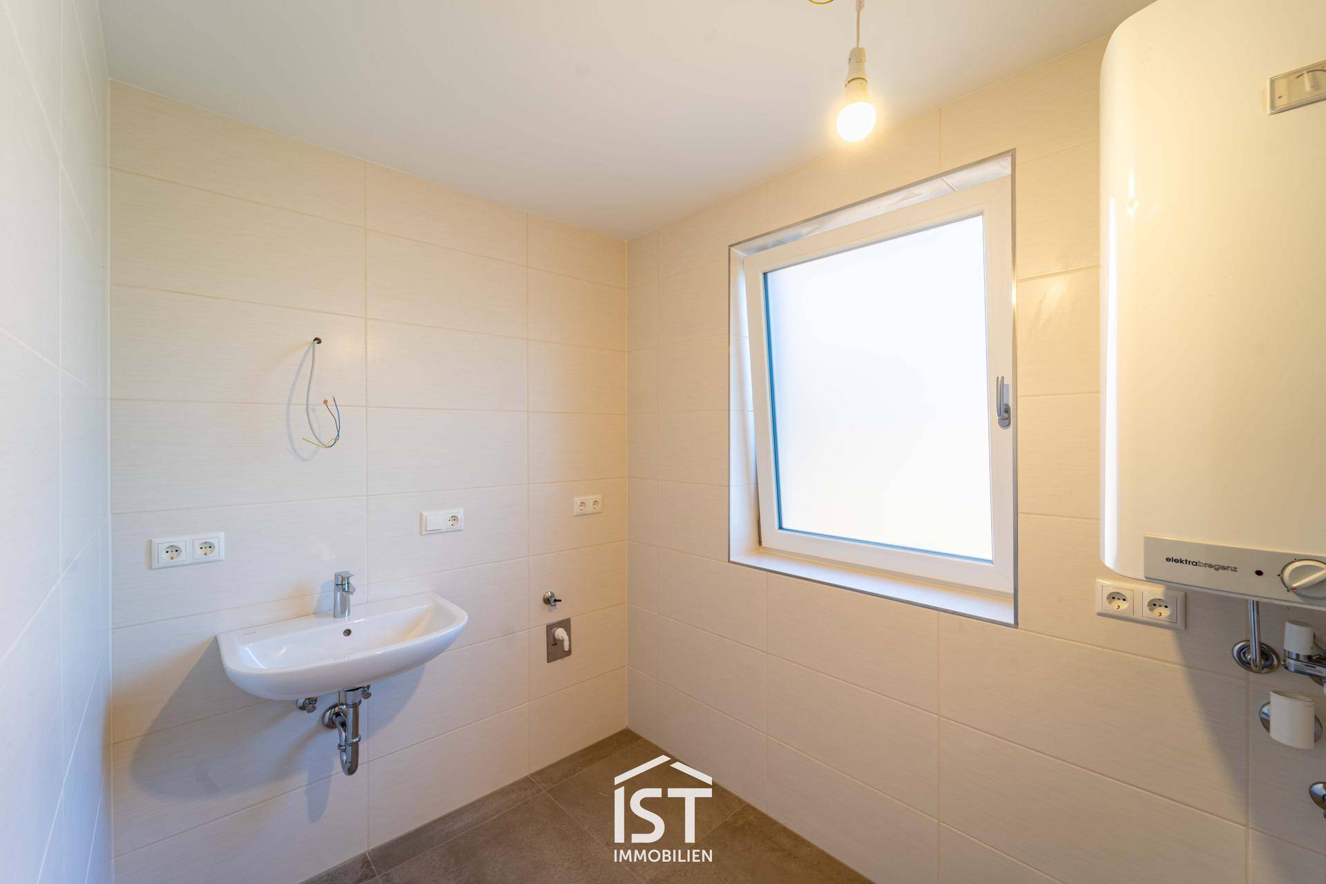 Funktionaler Raum mit Fliesenboden, Waschbecken und Warmwasserbereiter, ausgestattet mit einem Fenster.