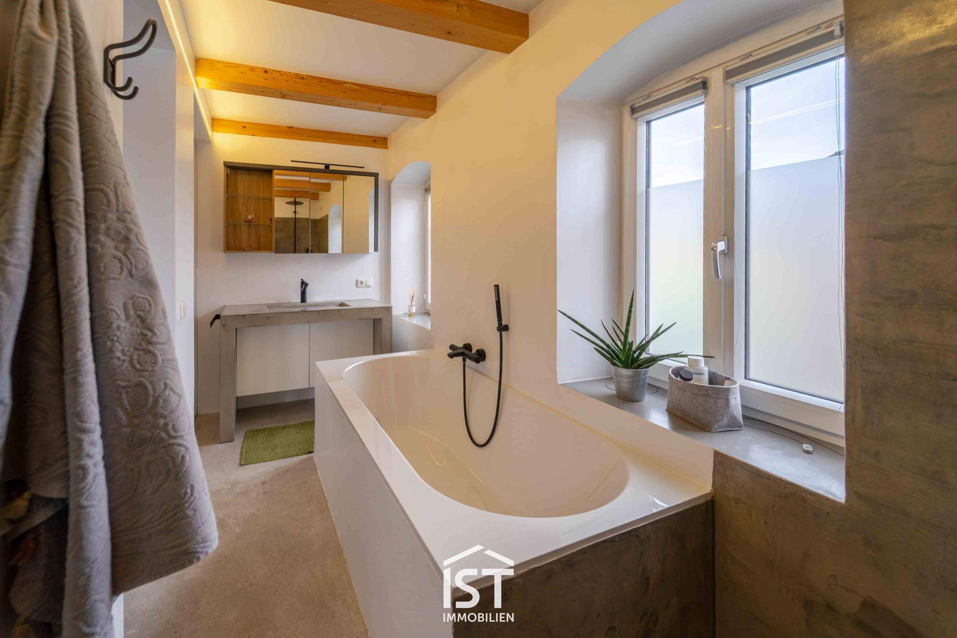 Helles Badezimmer mit Badewanne, Fenster und modernem Waschtisch.