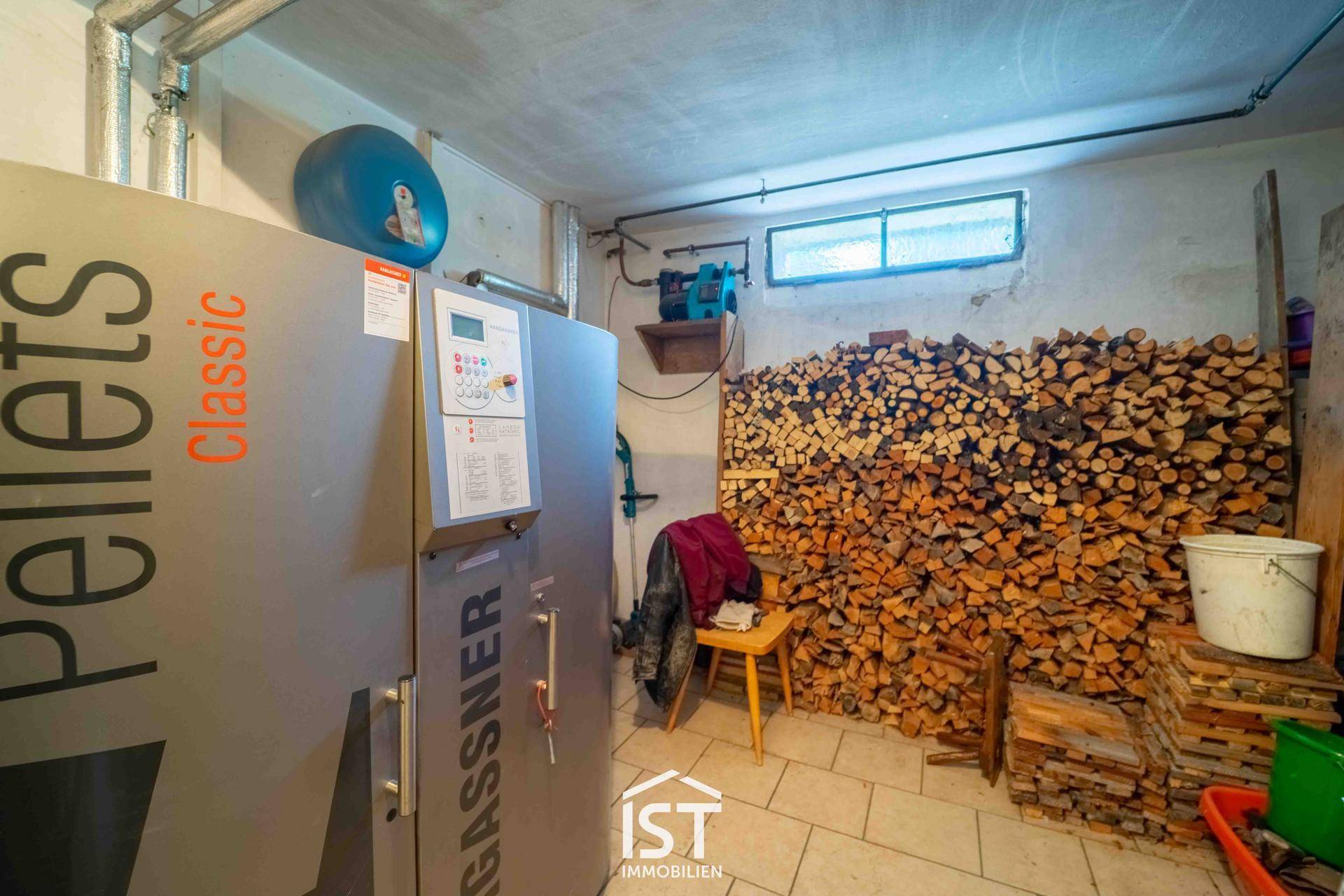 Heizraum mit Pelletkessel und großem Holzstapel für die Heizung.