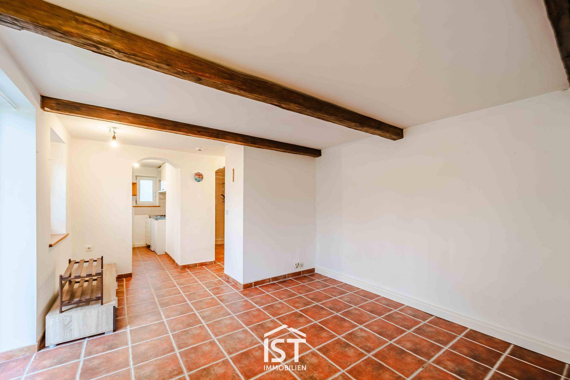 Wohnraum mit Terrakottafliesen und sichtbaren Holzbalken an der Decke.