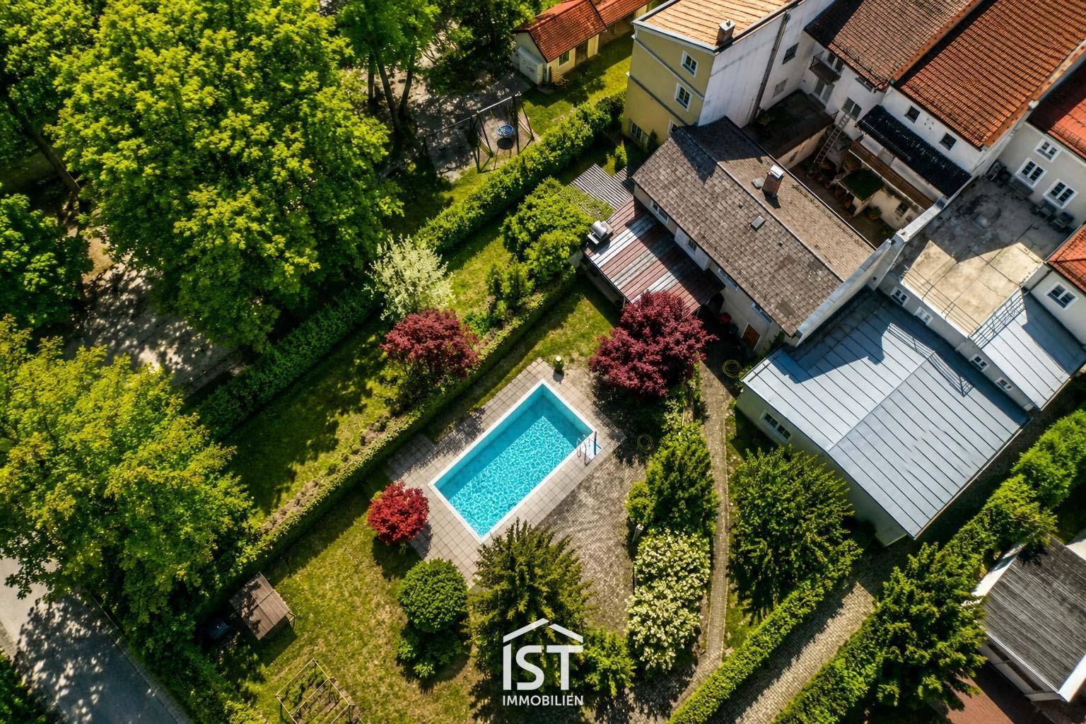 Luftaufnahme eines Anwesens mit Garten, Swimmingpool und umliegenden Häusern.
