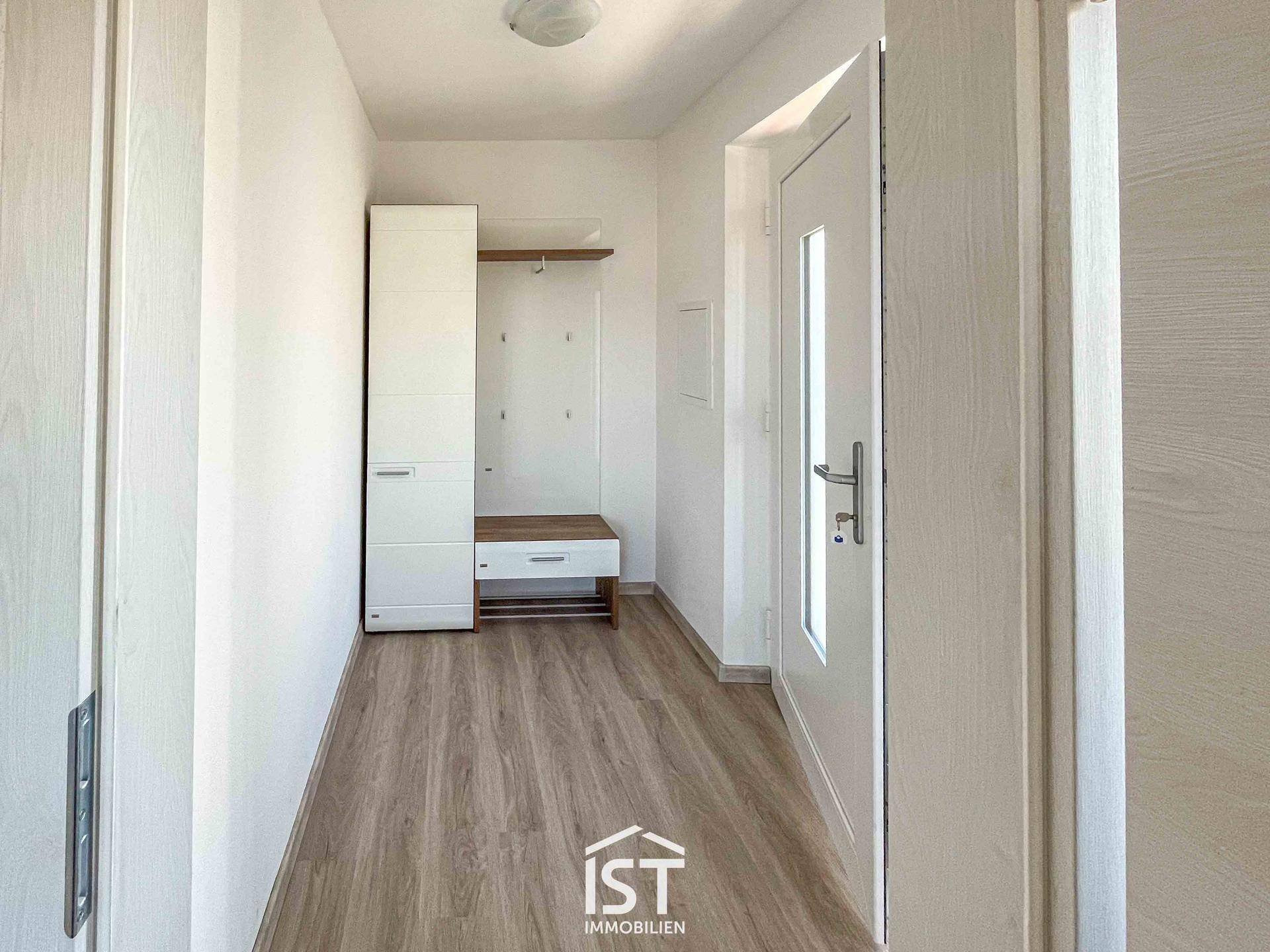 Heller Eingangsbereich mit Garderobe, Schuhbank und Laminatboden.