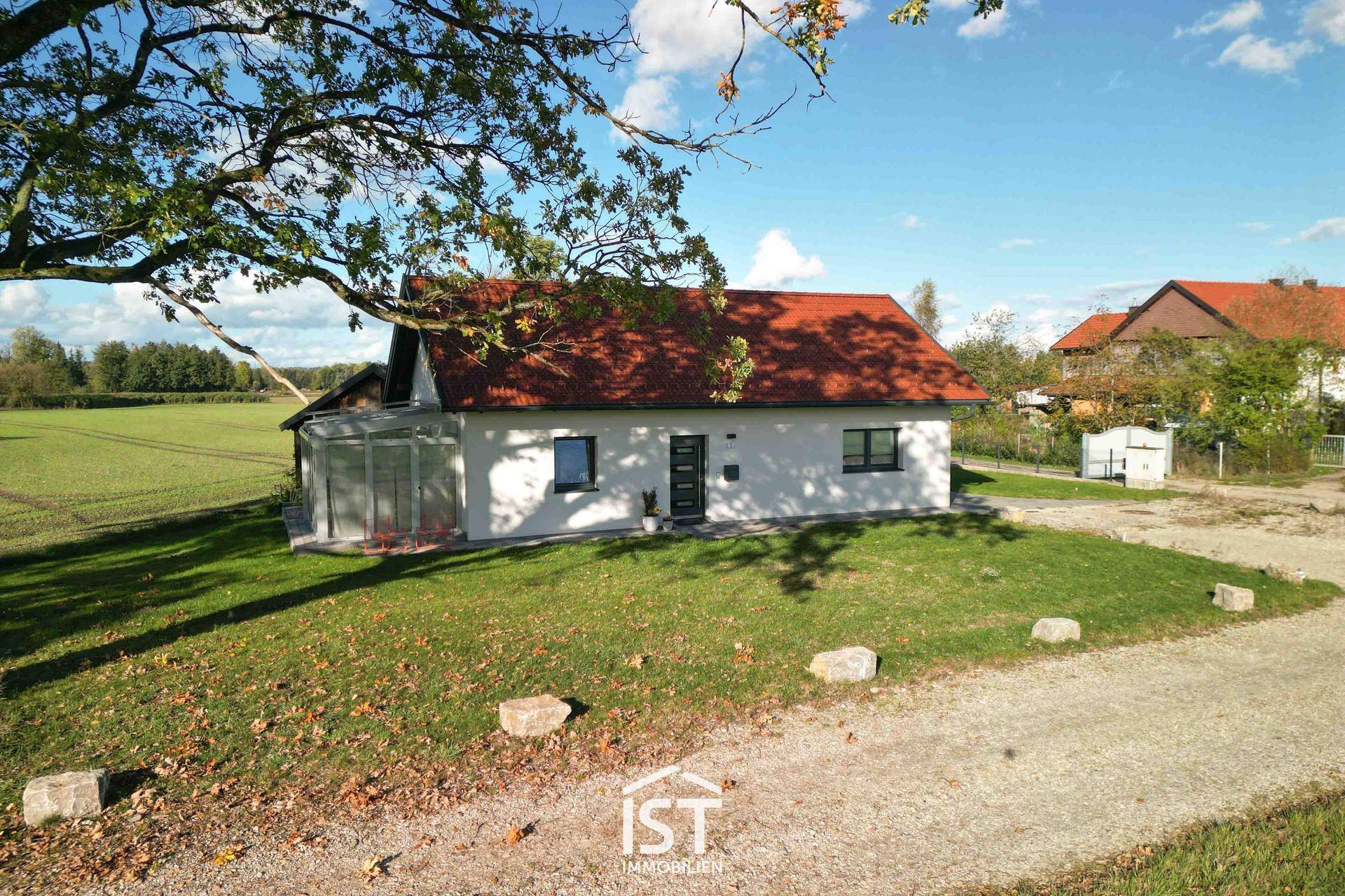 Ansicht des Einfamilienhauses mit Wintergarten und weitläufiger Natur im Hintergrund.