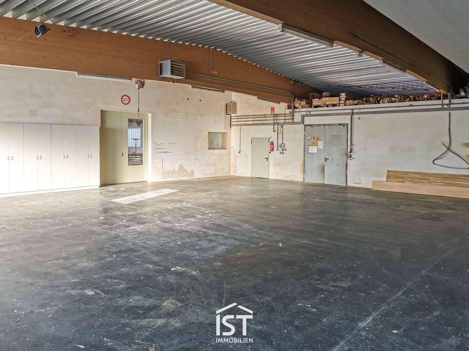 Großer, heller Lagerraum mit hoher Decke, Holzträgern und einem langen Schrank. Der Boden ist aus strapazierfähigem Beton.