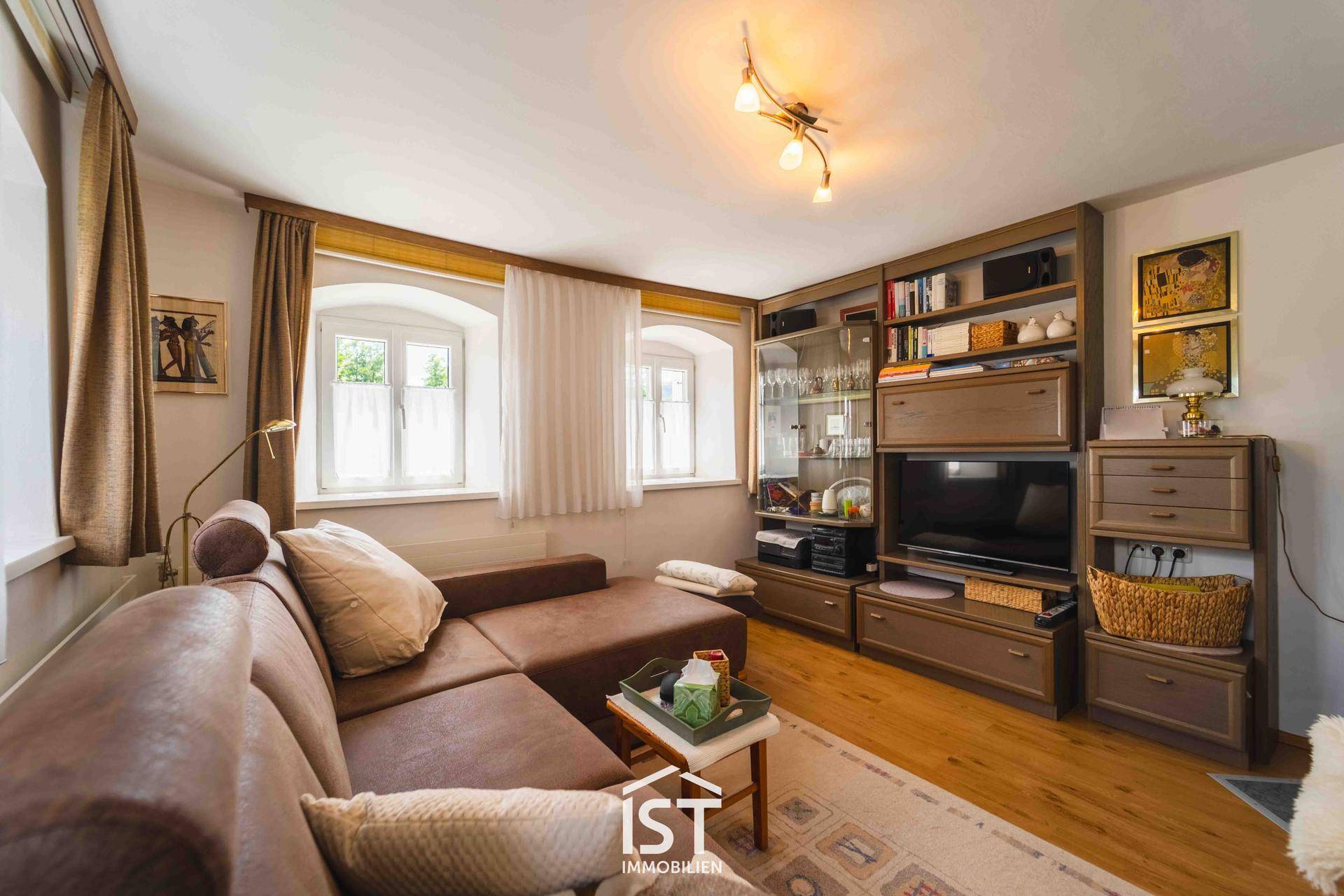 Wohnzimmer mit bequemer Eckcouch, Holzboden und traditionellen Möbeln, die zum Entspannen einladen.