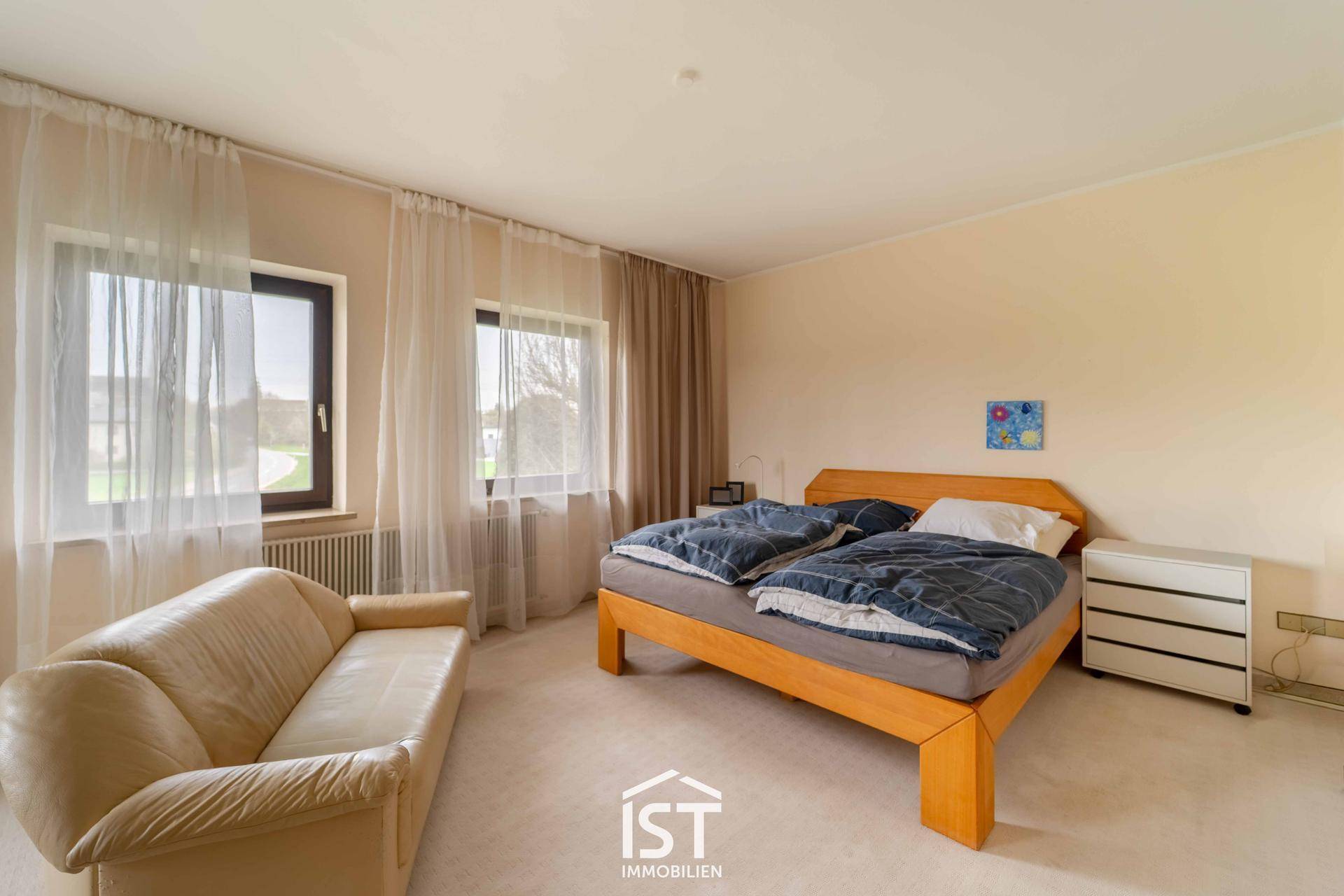 Geräumiges Schlafzimmer mit Teppichboden, Doppelbett und großen Fenstern für viel Licht.