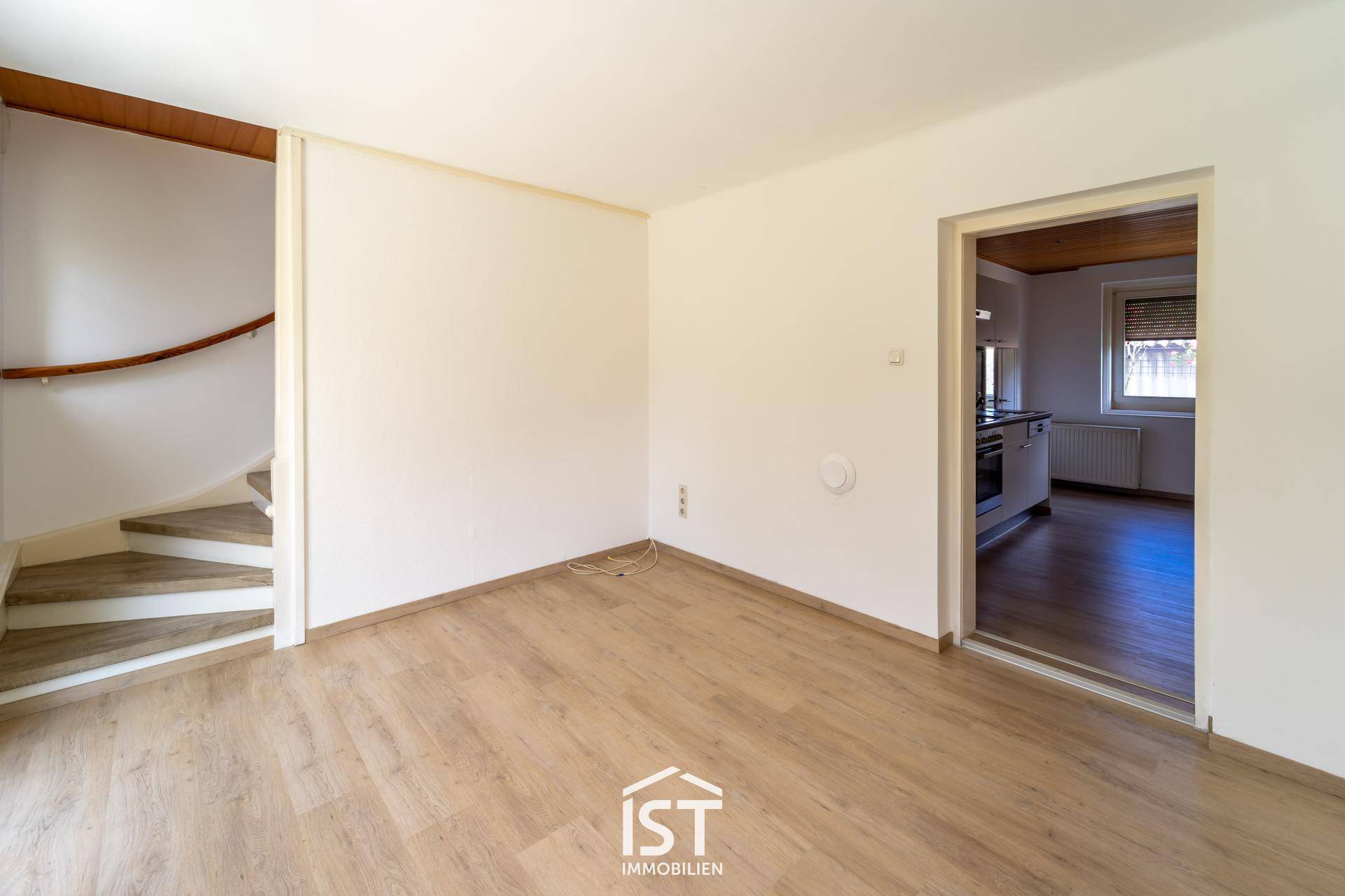 Heller Flur mit Laminatboden und Zugang zu einer Wendeltreppe sowie zur Küche.