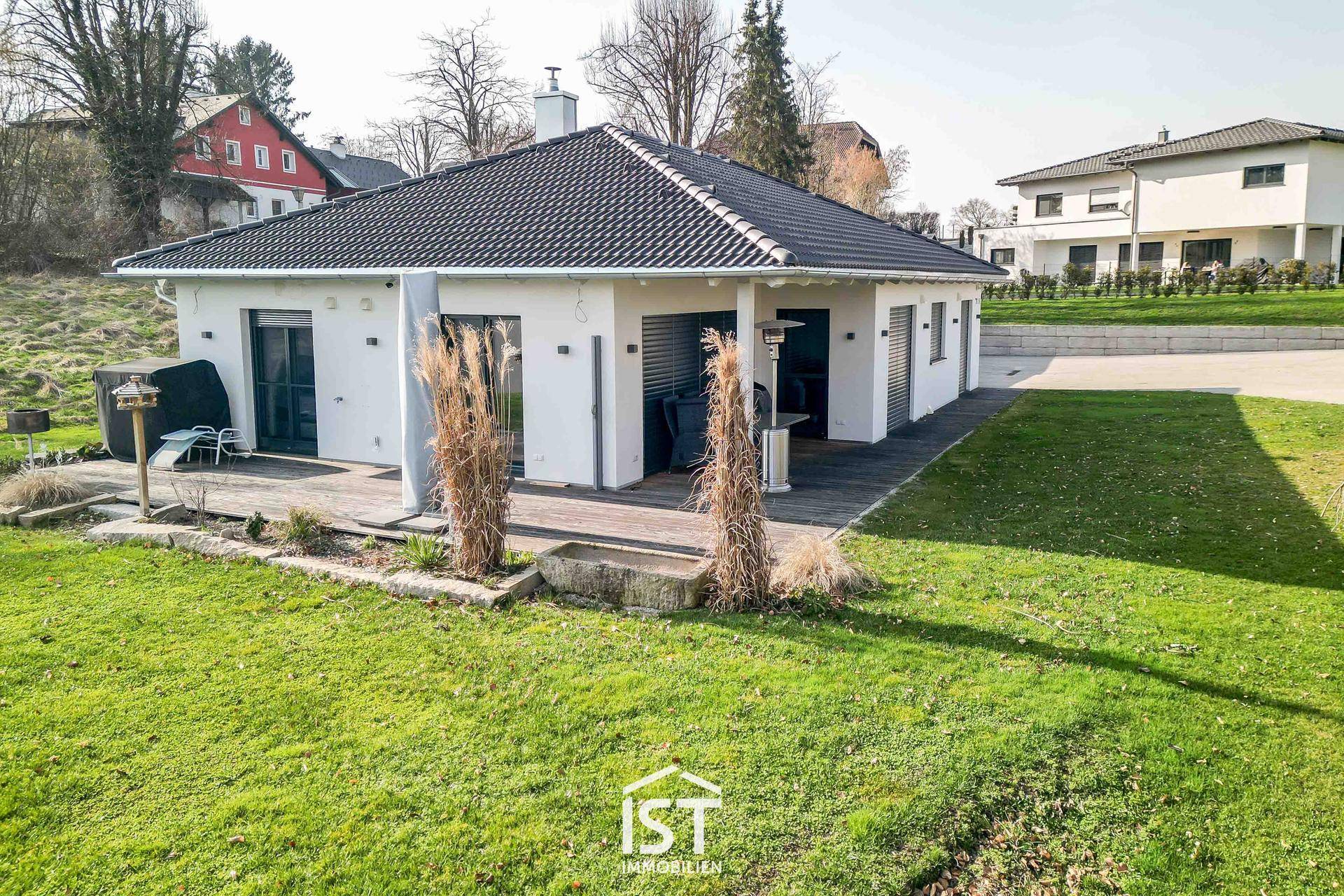 Rückansicht des Hauses mit gepflegtem Rasen und einer kleinen Terrasse mit Sitzgelegenheiten.