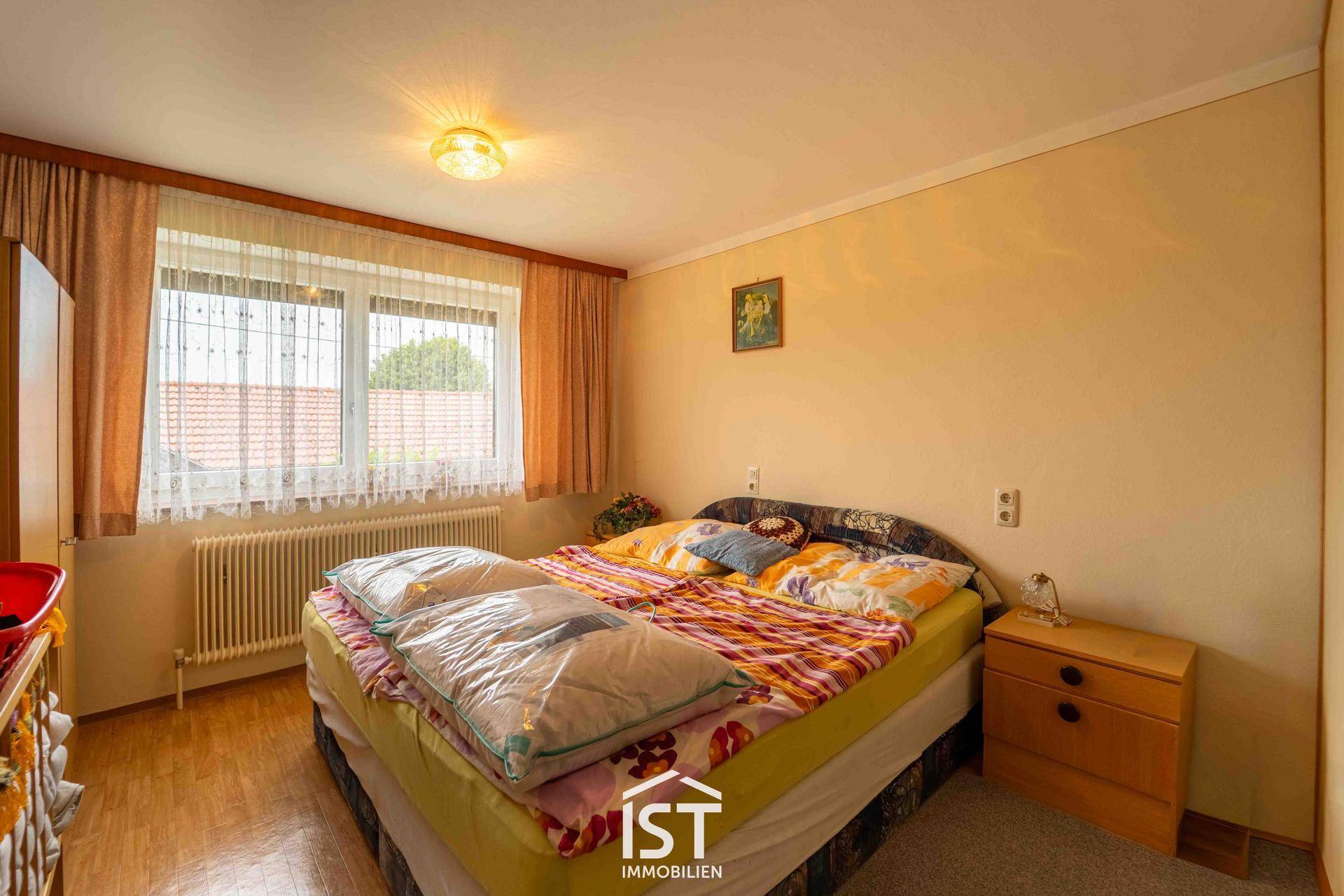 Gemütliches Schlafzimmer mit Doppelbett, Teppichboden und Fenster mit Blick nach draußen.