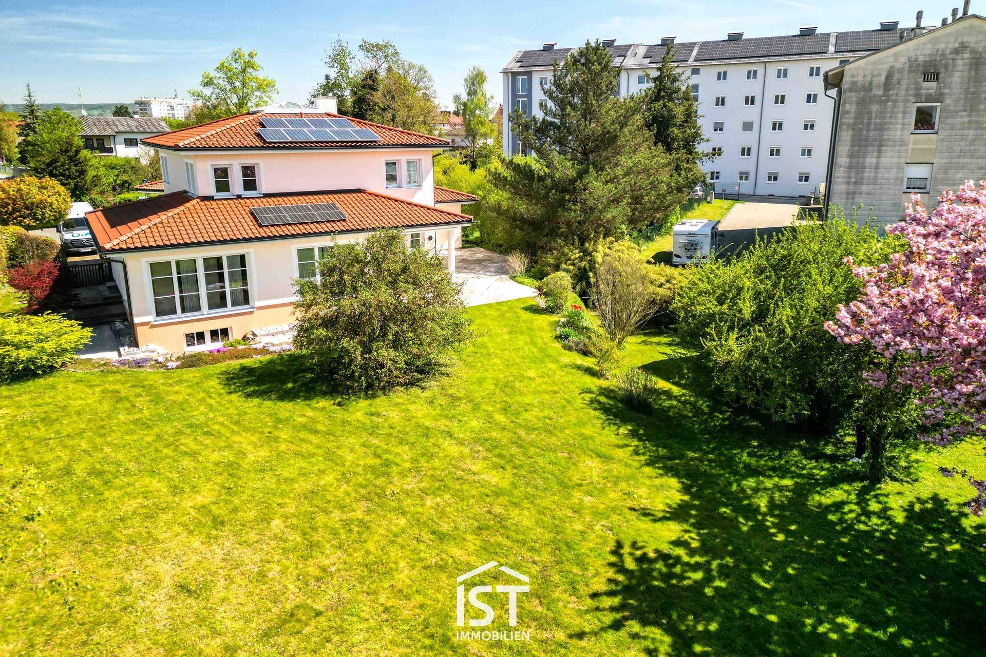Weitläufiger Gartenbereich mit blühenden Bäumen und Blick auf die umliegende Bebauung.