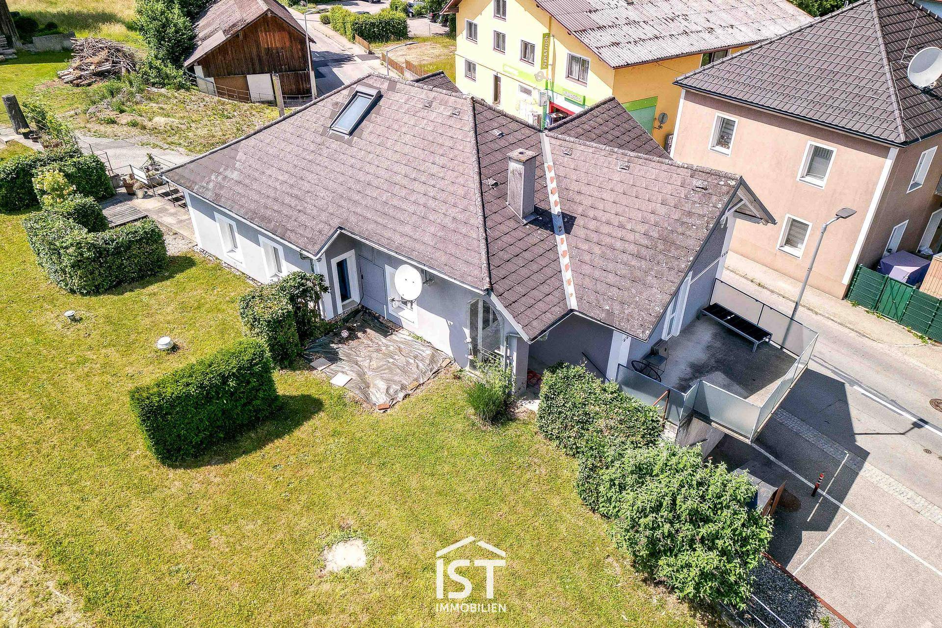 Rückseite des Hauses mit gepflegtem Gartenbereich, Terrasse und Blick auf die Umgebung.