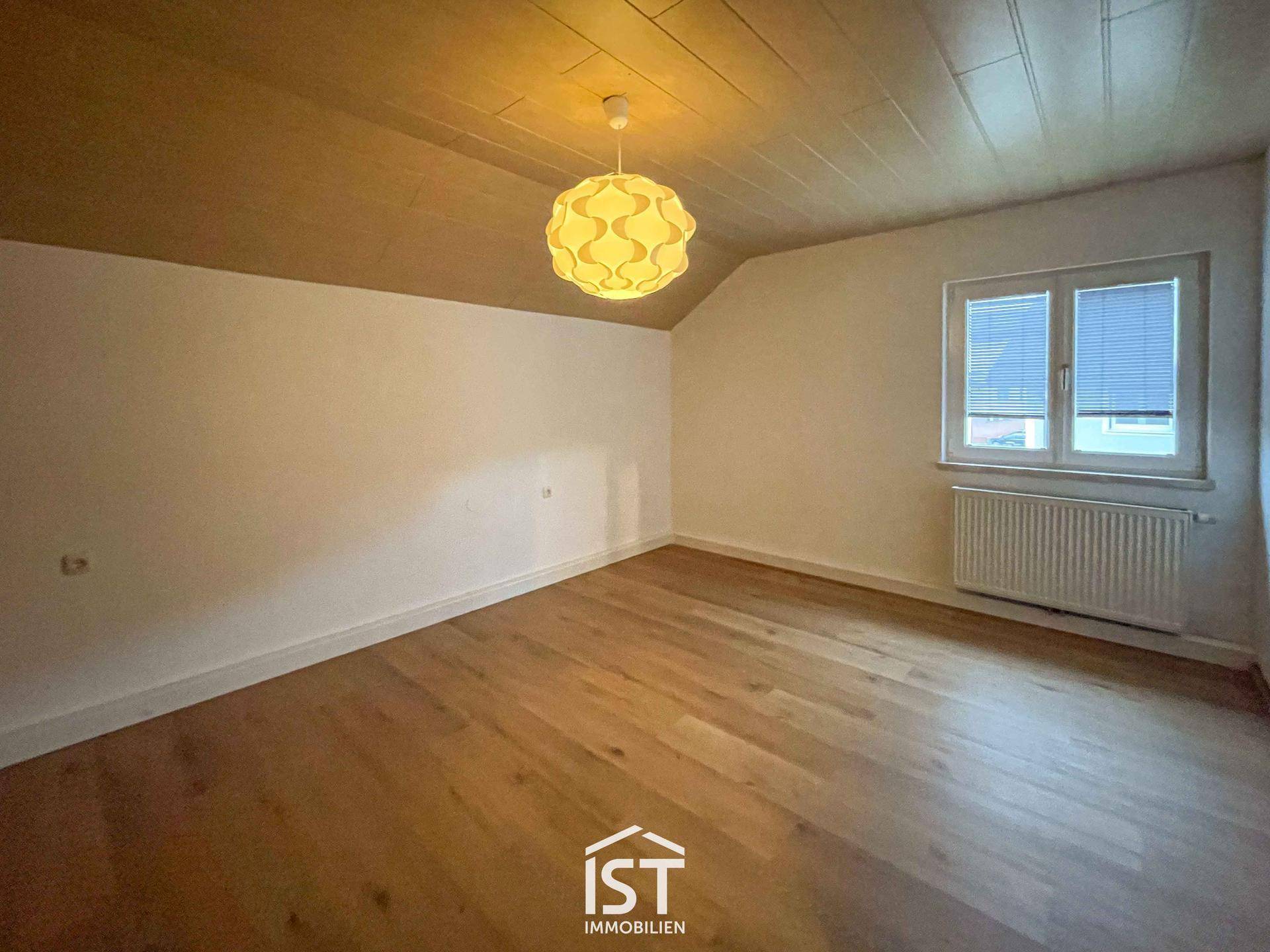 Helles Schlafzimmer mit Holzboden, Holzdecke und einem dekorativen Deckenlicht.