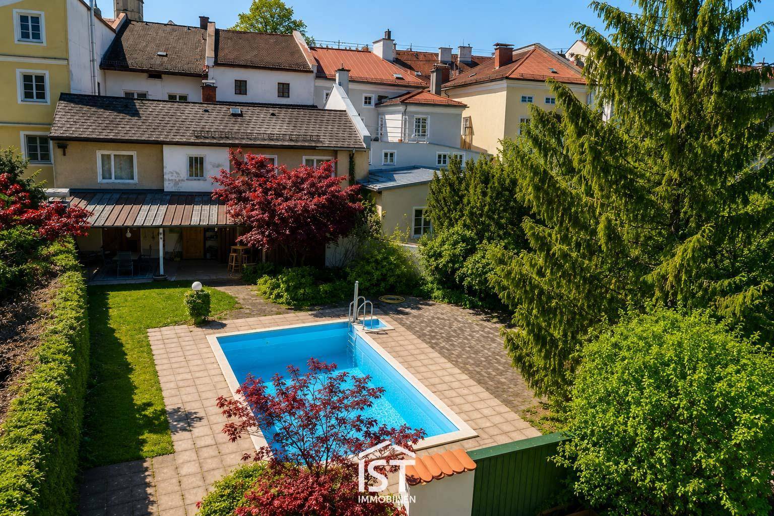 Gartenanlage mit Swimmingpool, umgeben von Bäumen und Hecken, aus der Vogelperspektive.