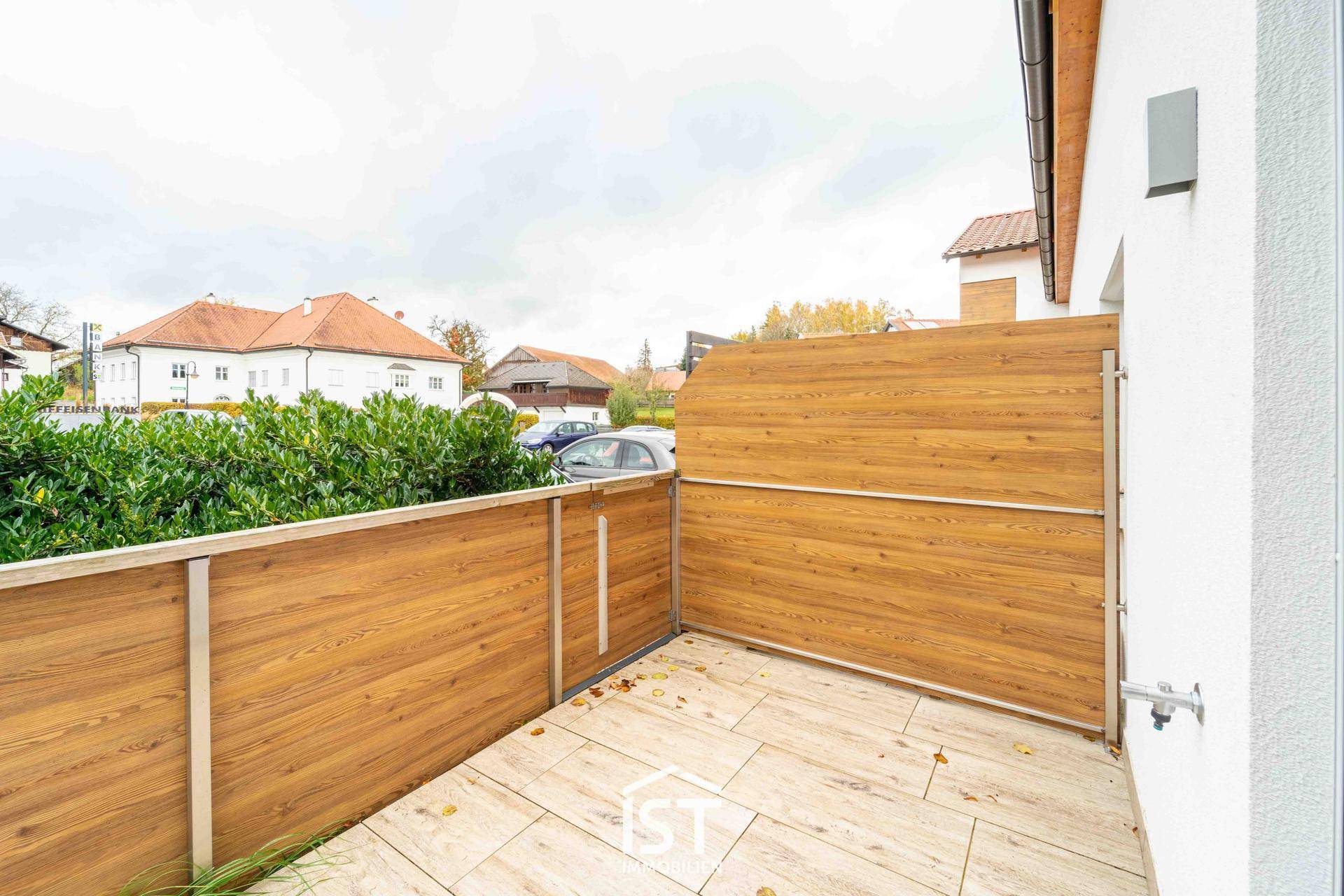 Kleine Terrasse mit Holzsichtschutz und Fliesenboden, ideal für entspannte Stunden im Freien.